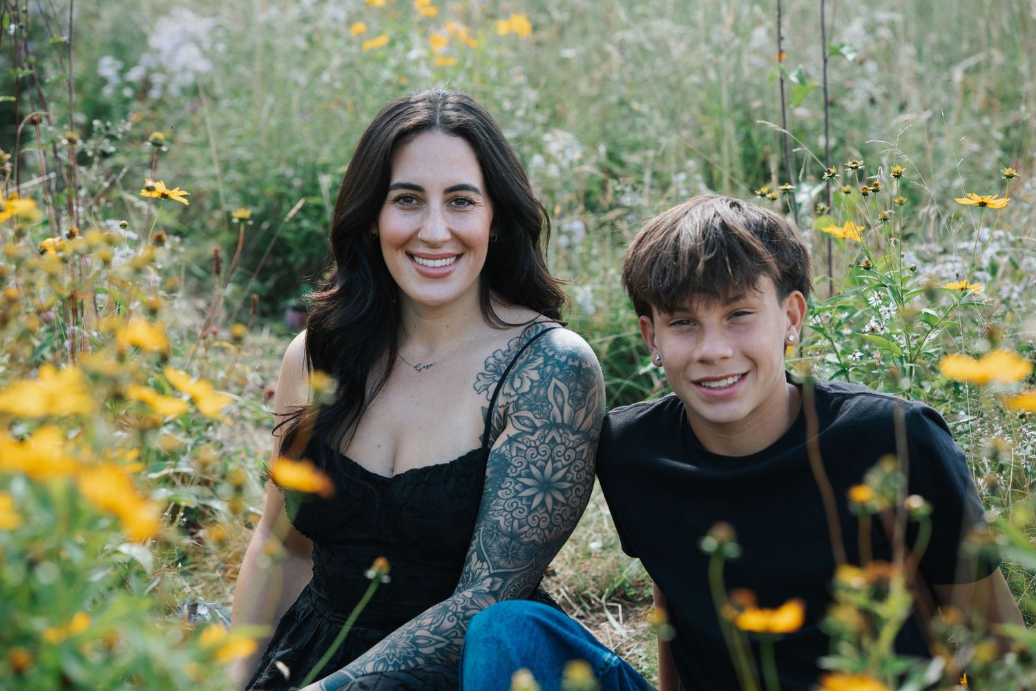 A couple shares joyful moments among blooming yellow wildflowers in a lush green outdoor setting.