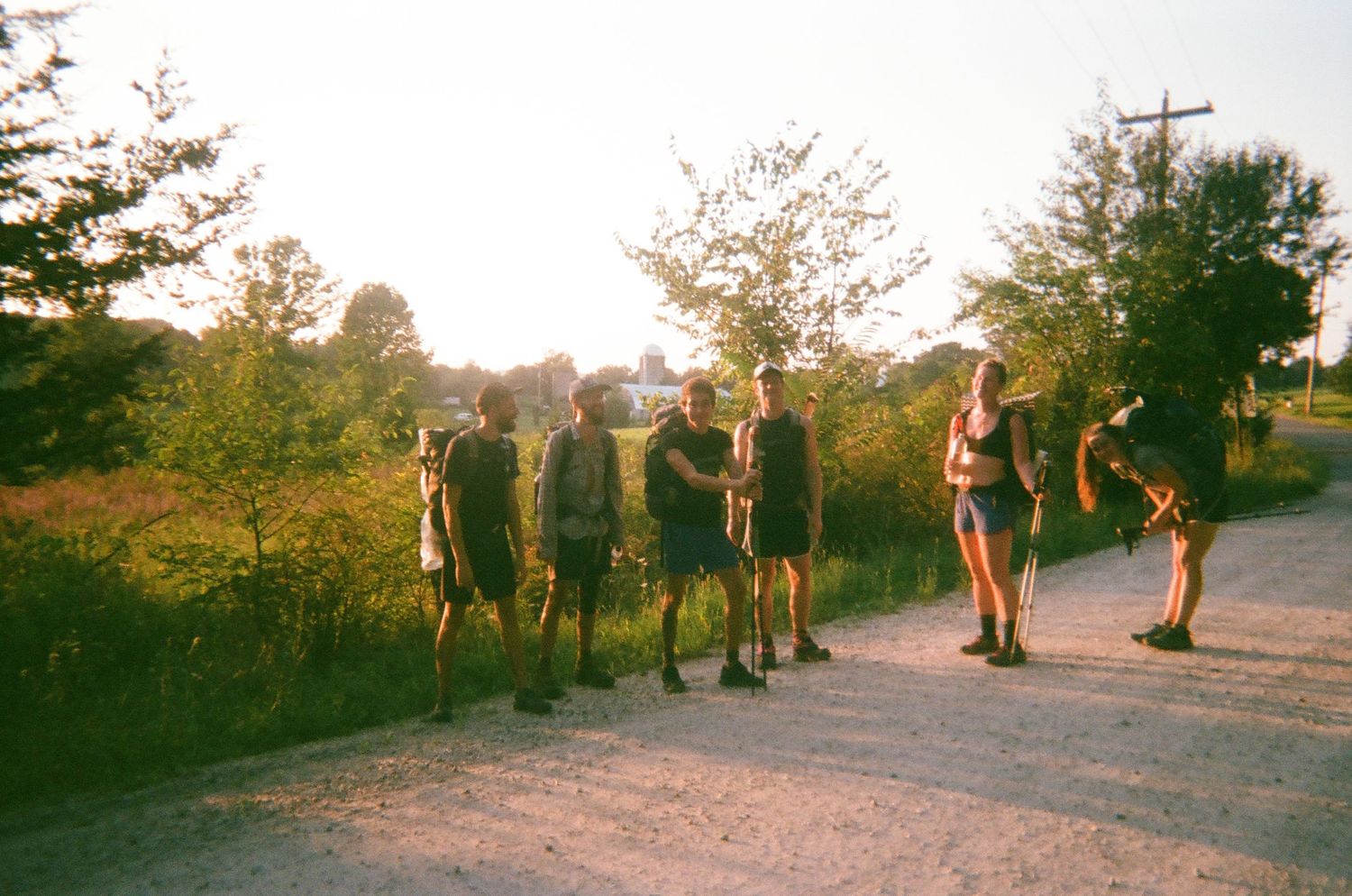 Group of hikers walking along a dirt path during golden hour.
