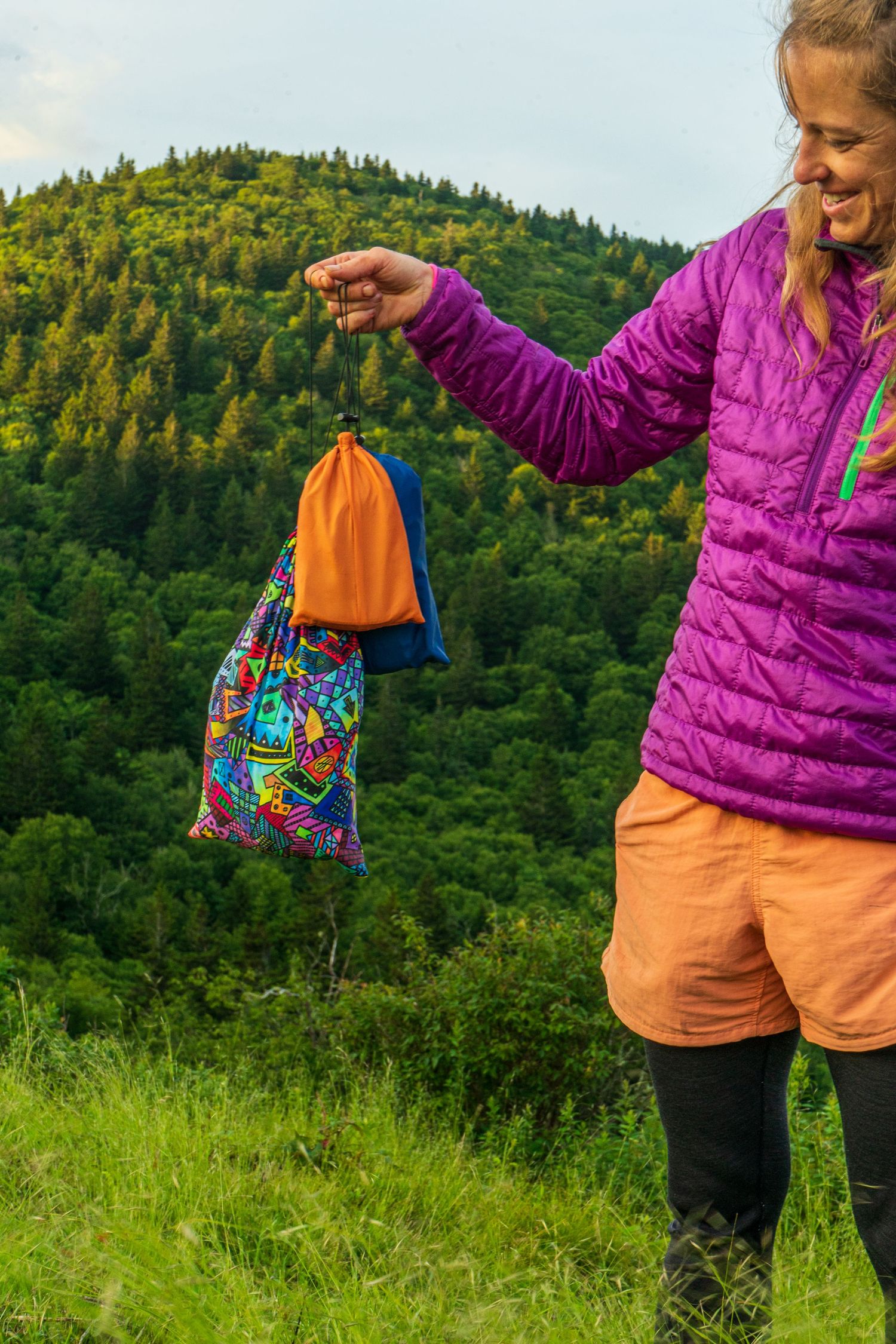 Colorful outdoor accessories and gear shown against mountain landscape background.