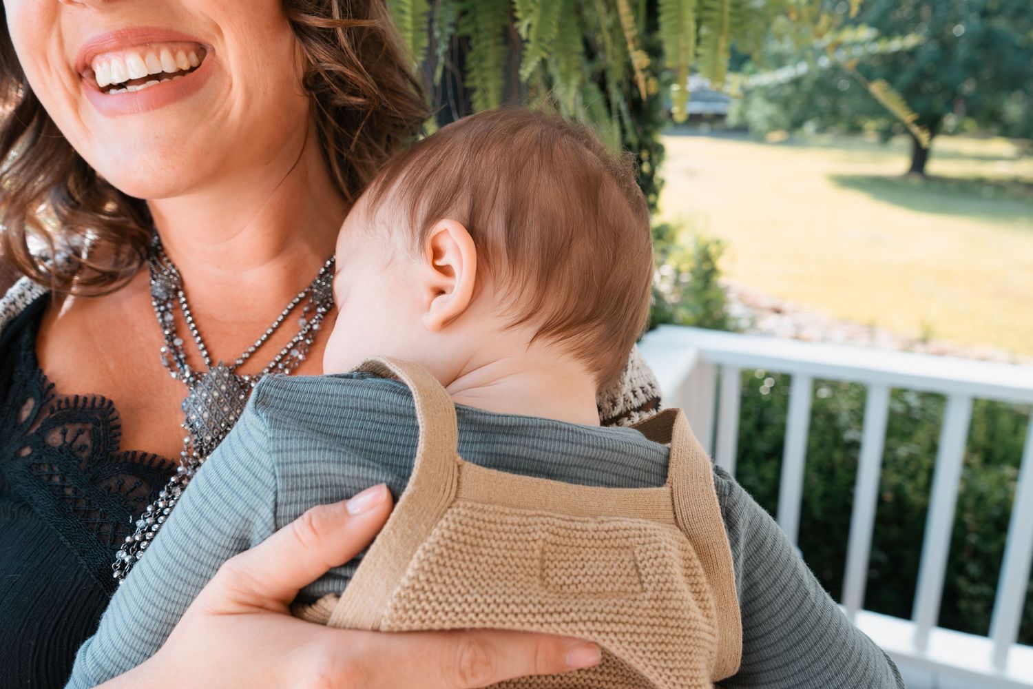 Close up of joyful moment on sunny porch with statement necklace detail.