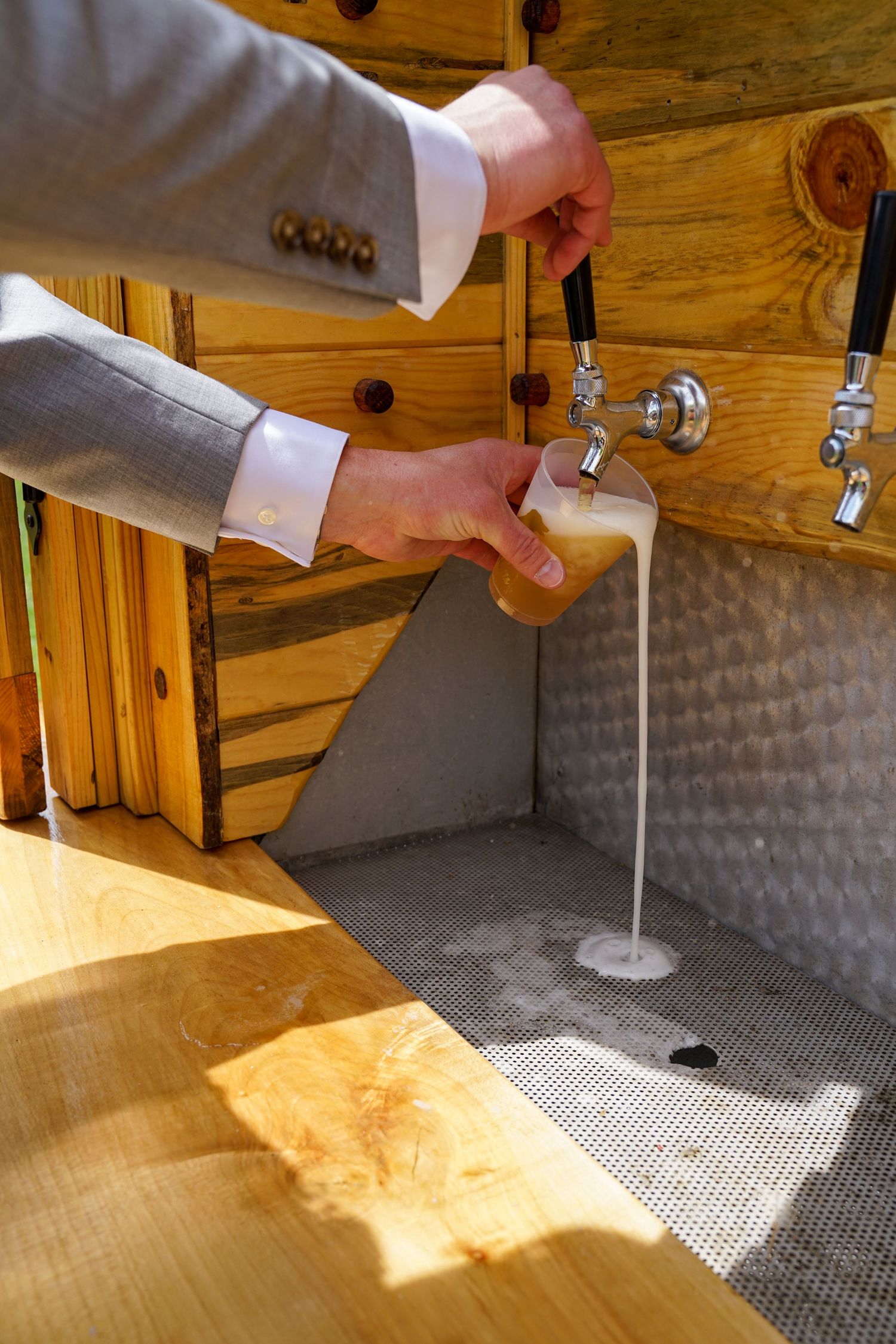 Beer being poured from a tap into a glass with a white foam head forming on top.