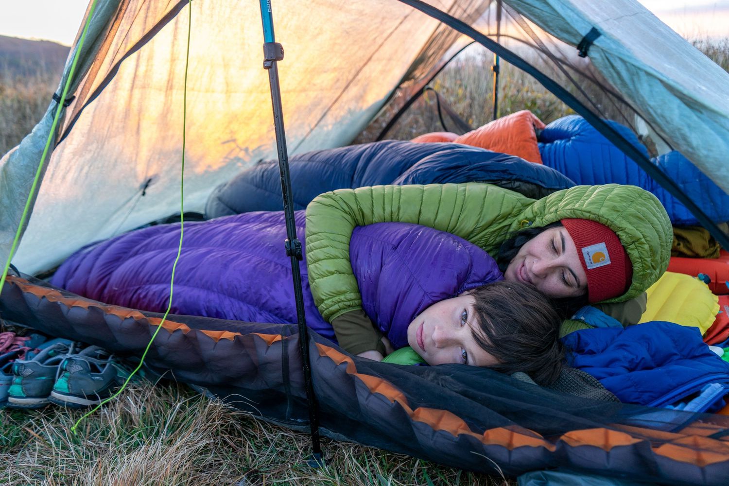 Cozy tent interior with colorful sleeping bags during sunset camping adventure.