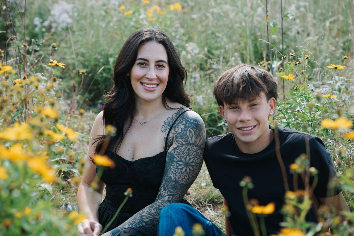 A couple shares a joyful moment together surrounded by blooming yellow wildflowers in a meadow.