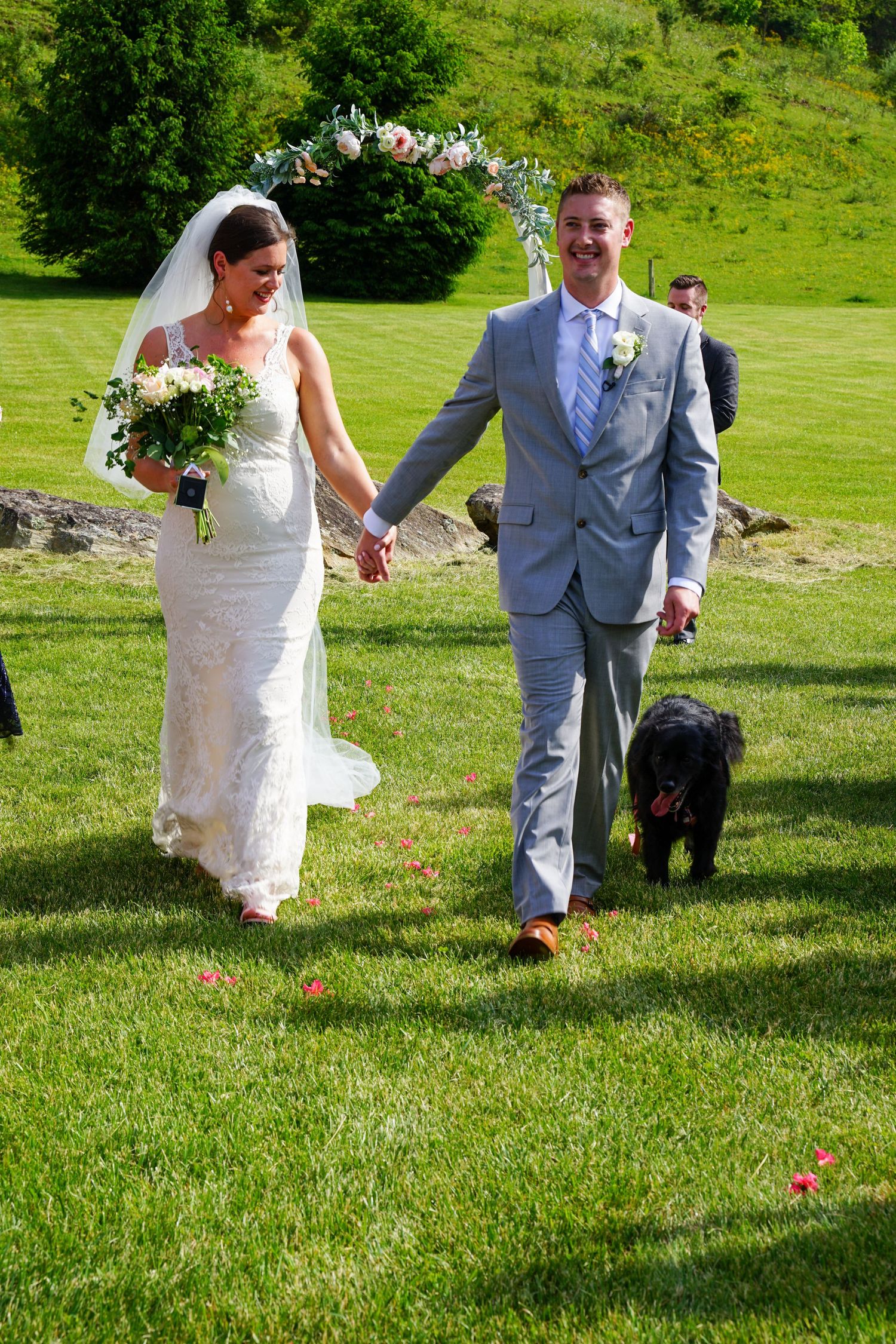 Newlywed couple plays croquet on a lush green lawn during their wedding celebration at an outdoor venue.