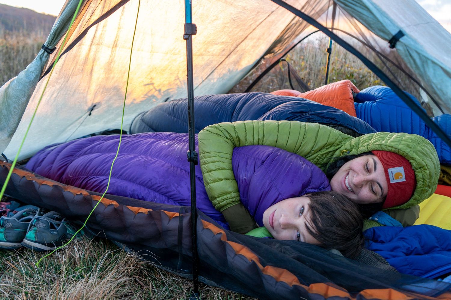 Colorful sleeping bags lined up in tents during a camping trip in the wilderness.
