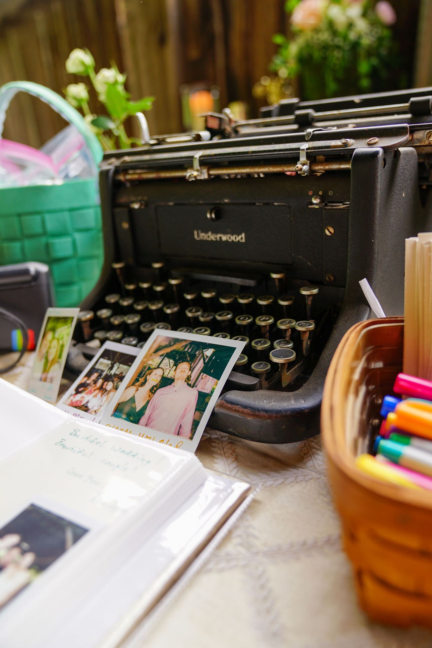 A vintage Underwood typewriter sits next to colorful markers and paper on a wooden desk surface.
