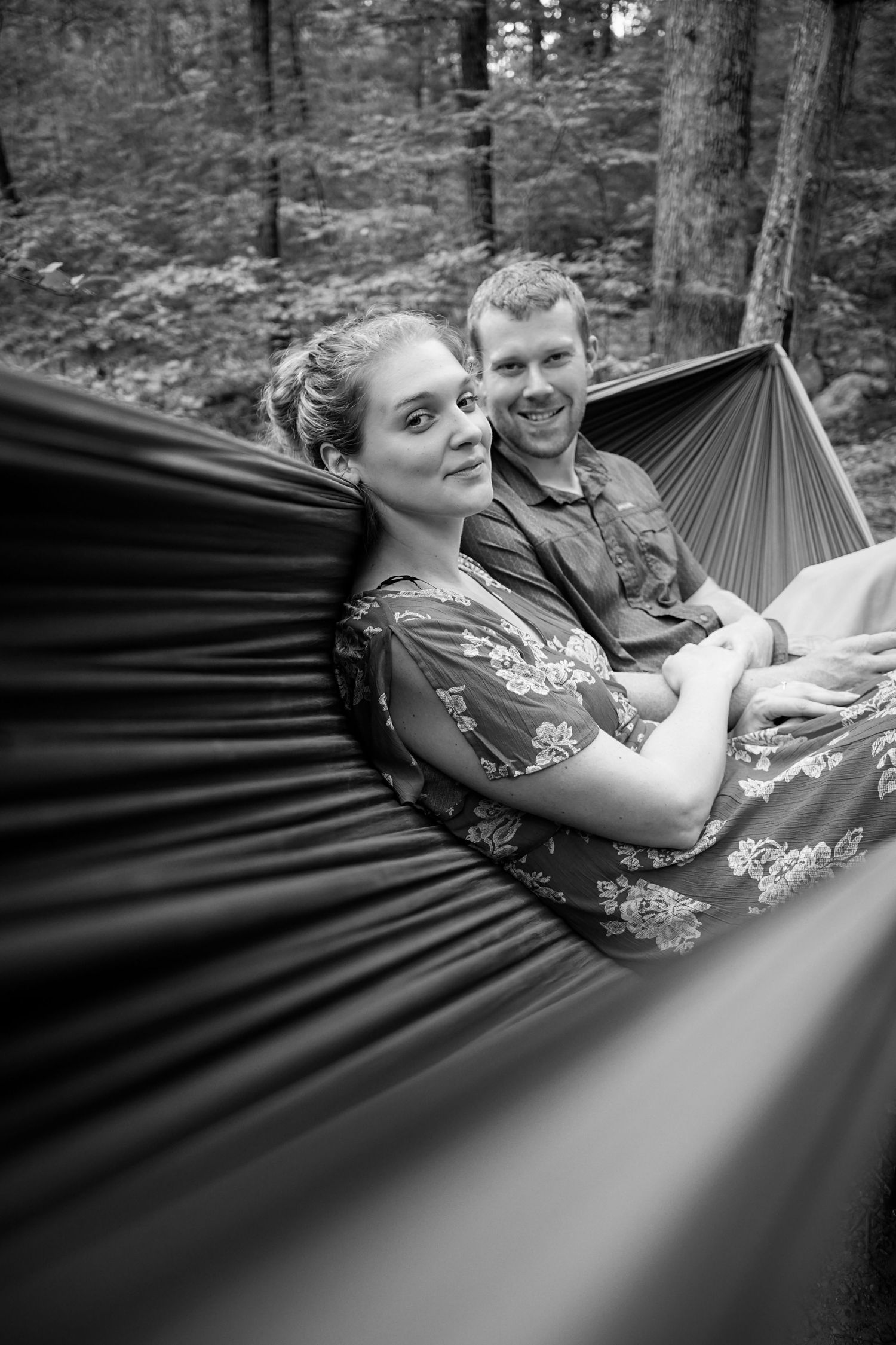 Black and white sequence shows couple relaxing together in hammock among forest trees.