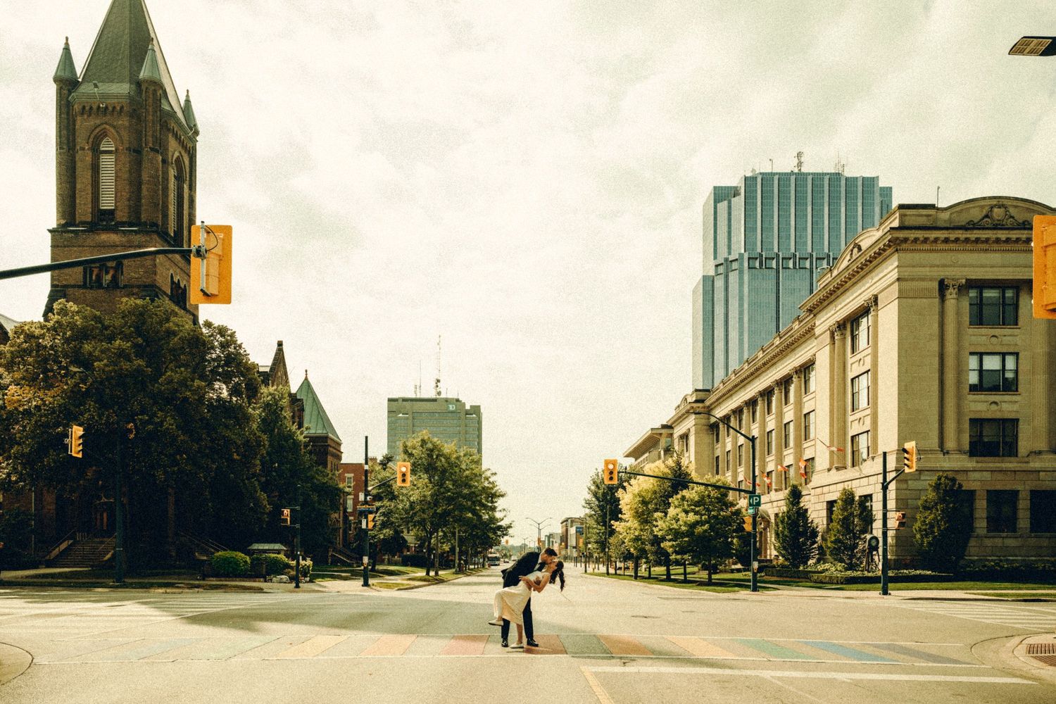 Wide shot of bride and groom standing together on a quiet city street on wedding day.