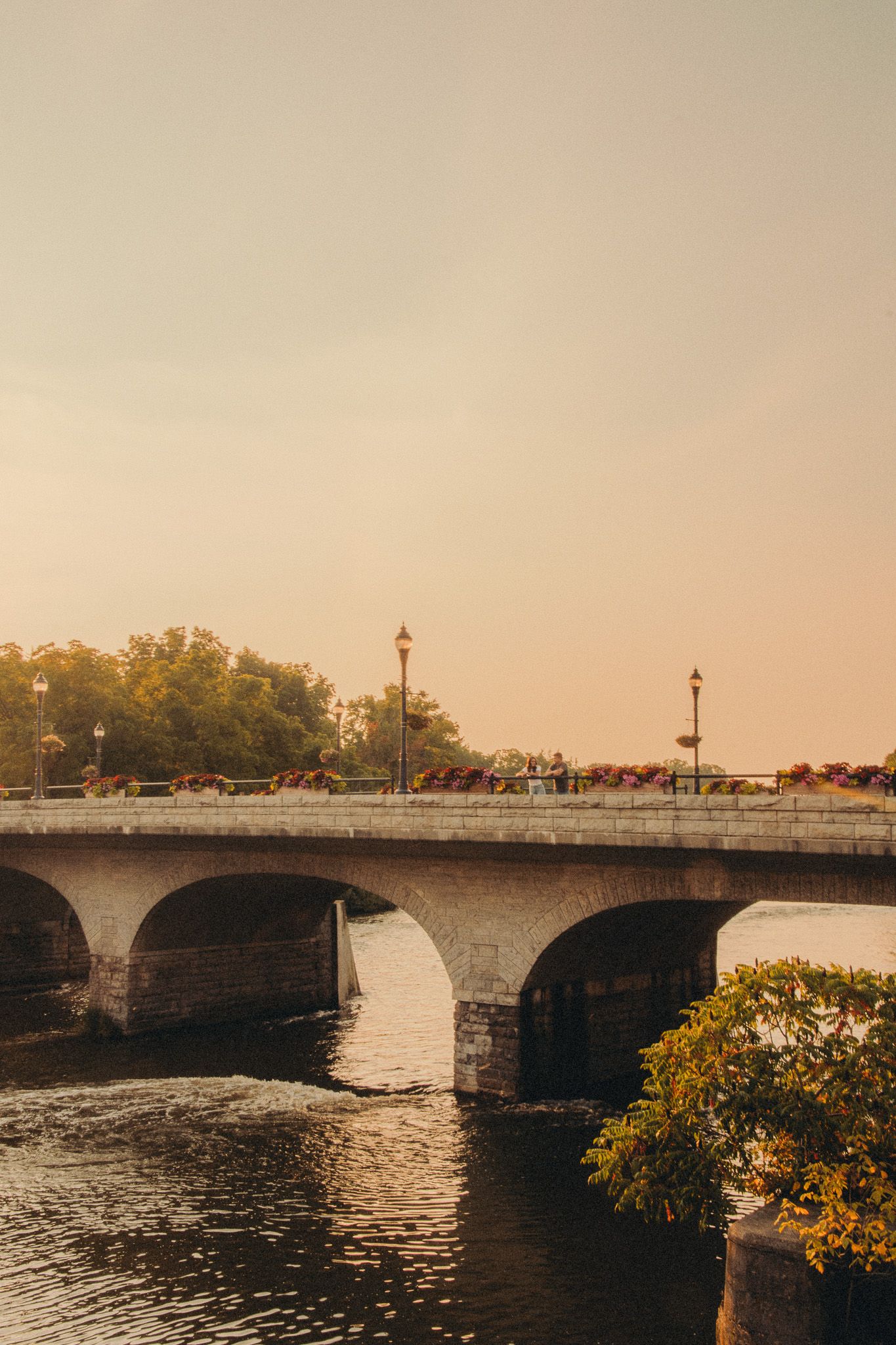 Stone bridge with arches over river at warm sunset glow.