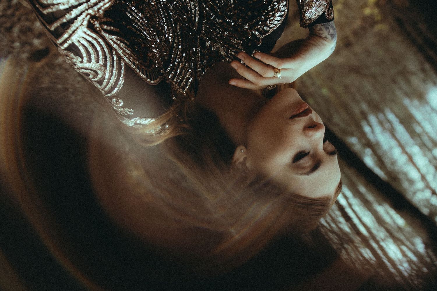A woman in a sequined outfit is captured in a dreamy, swirling artistic portrait with warm tones.