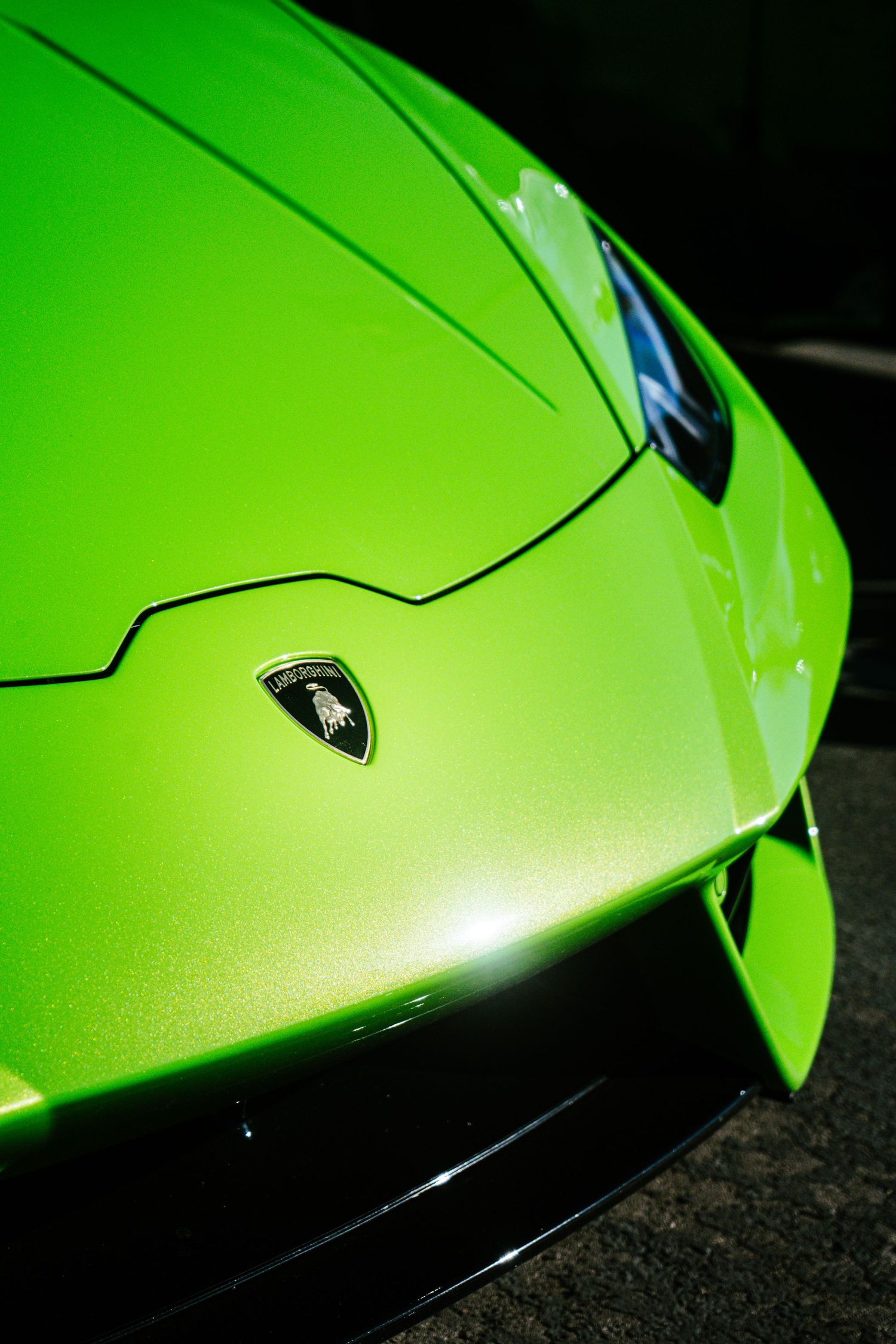 Close-up of a vibrant lime green Lamborghini Huracan front hood and iconic shield logo.