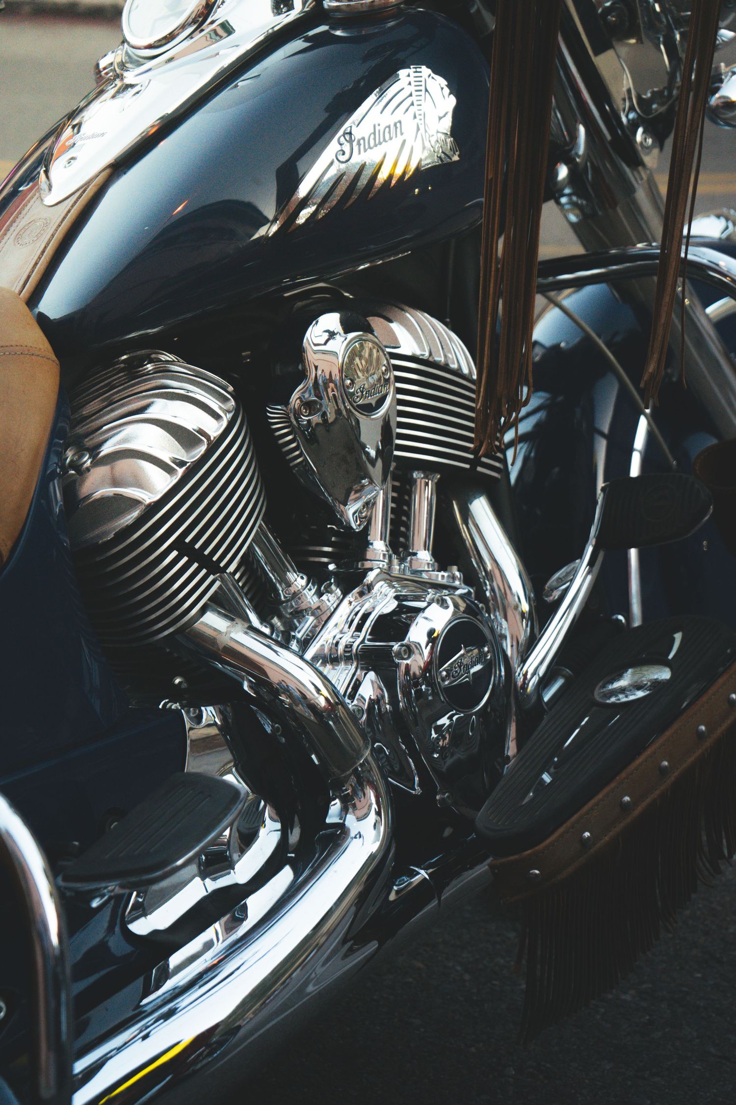 Shiny chrome Indian motorcycle engine with V-twin cylinders and classic logo badge in natural light.