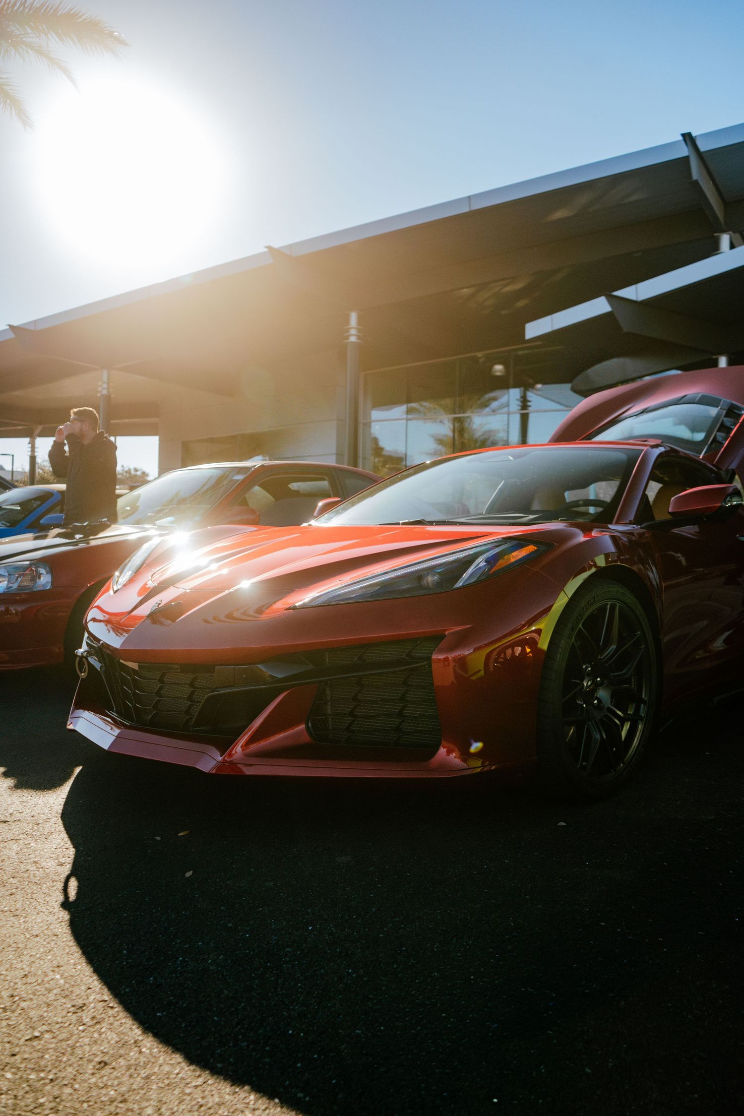 Gleaming red Chevrolet Corvette C8 Z06 parked at Chapman Automotive Cars and Coffee event in bright sunlight.