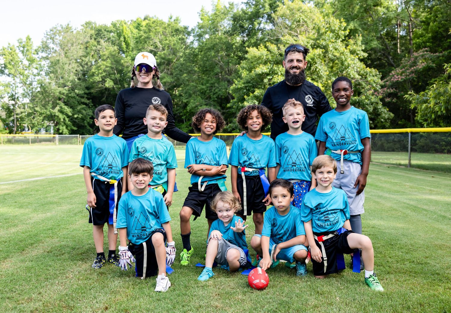 Youth soccer team in blue jerseys posing together on grass field.