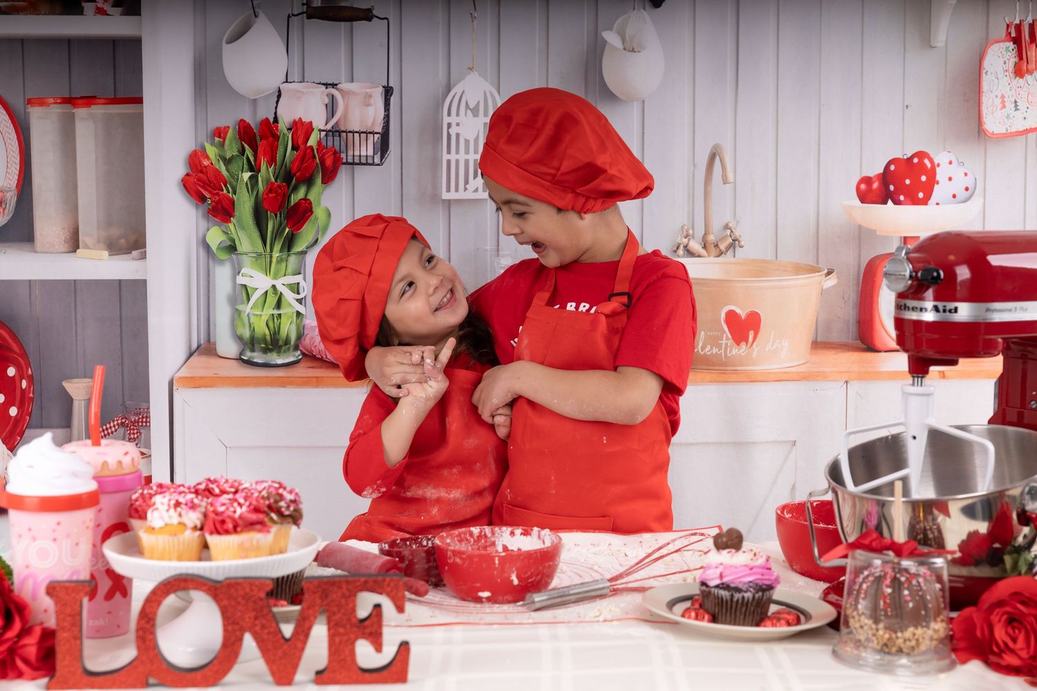 Valentine's Day themed kitchen setup with red decorations, flowers, and baked treats.