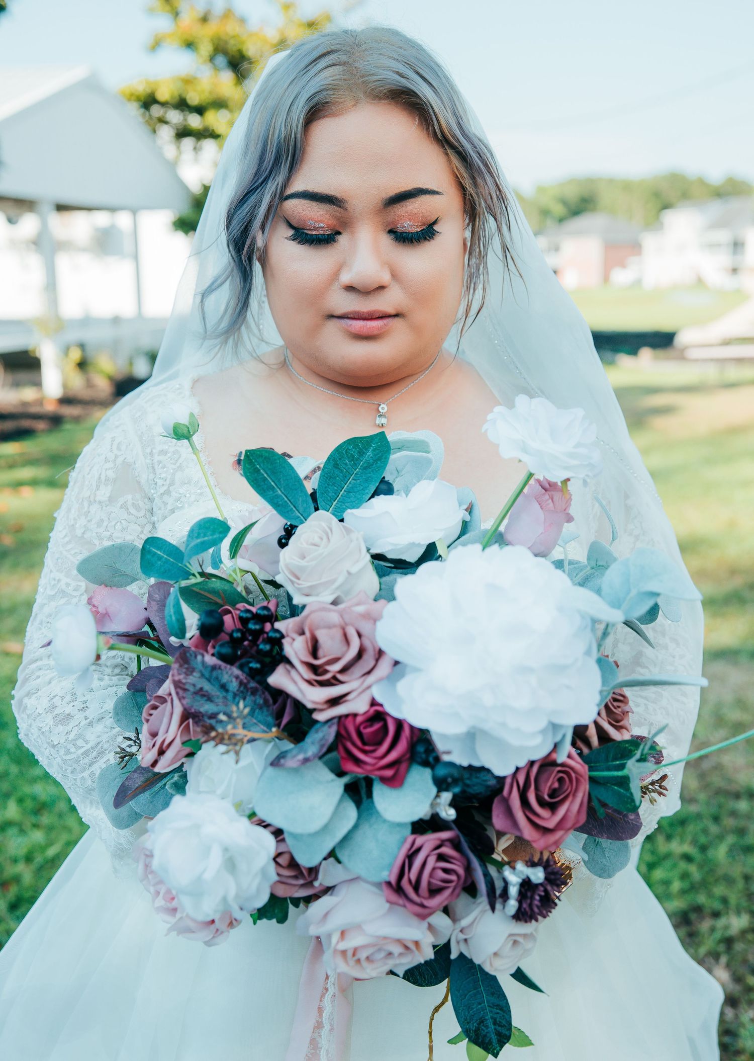 Close-up of a romantic bridal bouquet featuring mauve roses, white flowers, and teal foliage.