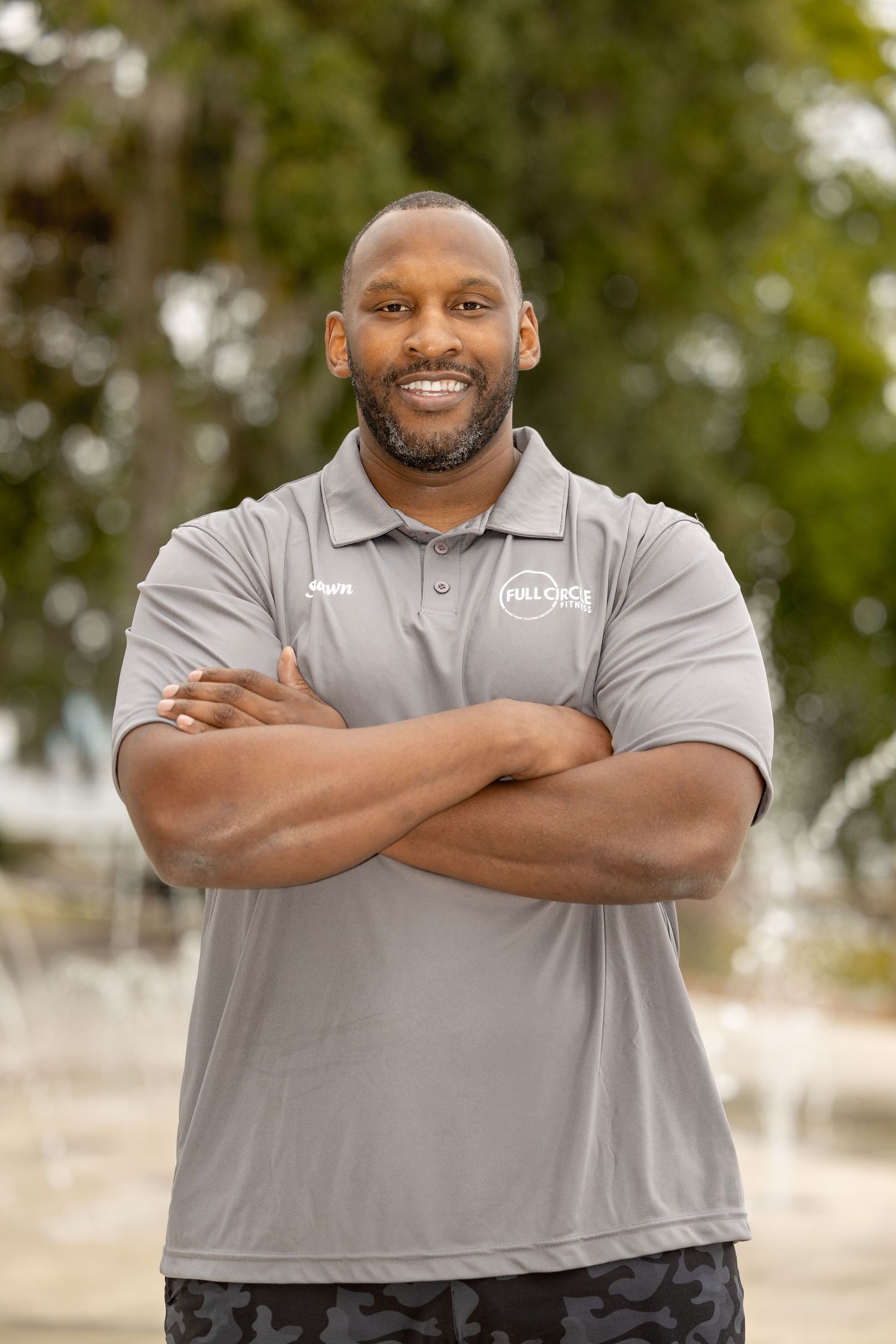 Person wearing grey company polo shirt shown in casual poses against natural outdoor background.