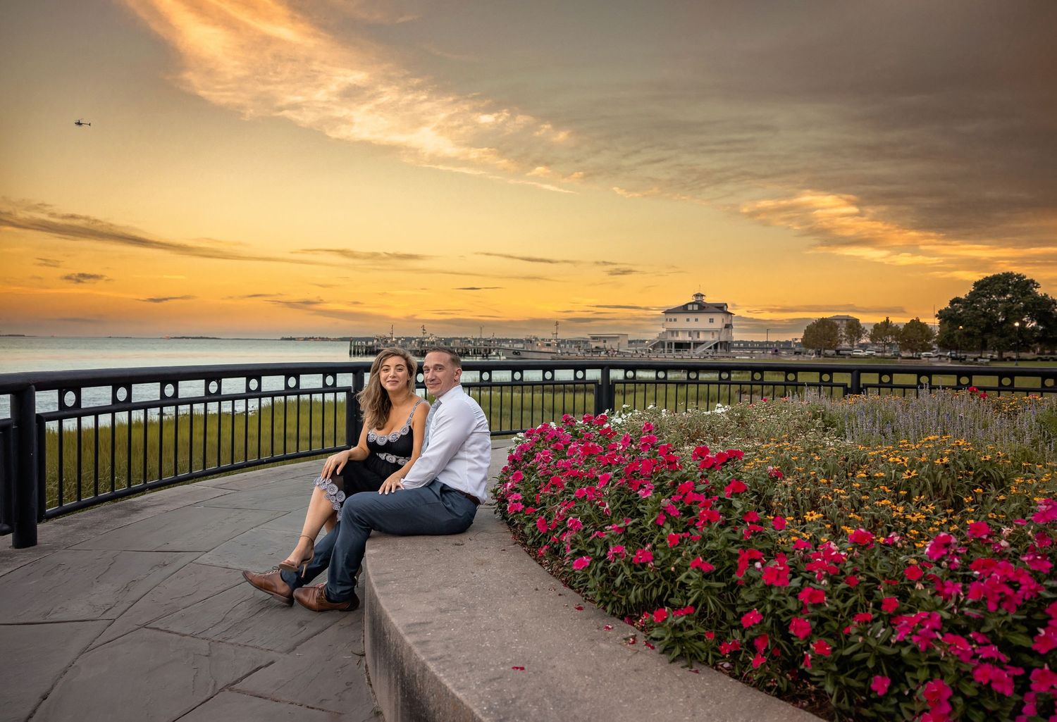Sunset engagement photos by iconic Charleston pineapple fountain with pink flower gardens.
