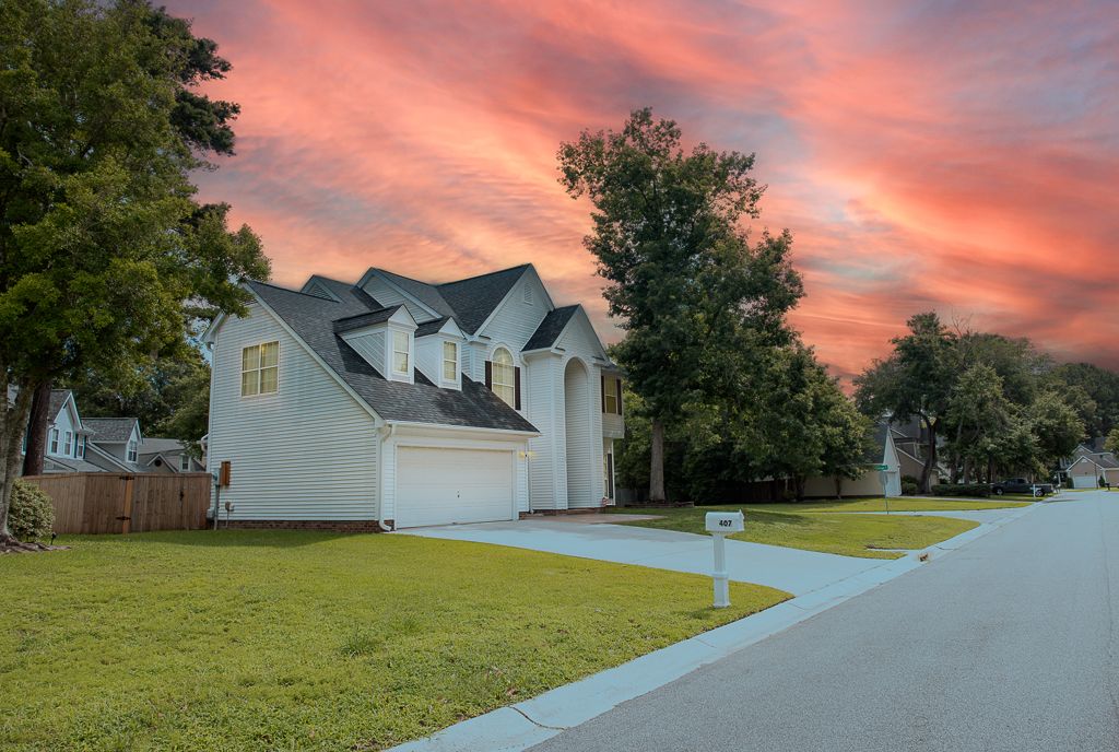 Two-story suburban house with white exterior under dramatic pink sunset sky.