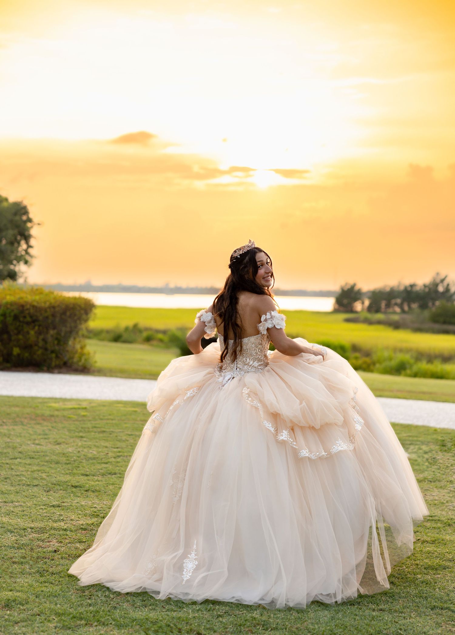 Bride in flowing white ballgown twirls during golden hour sunset photoshoot.