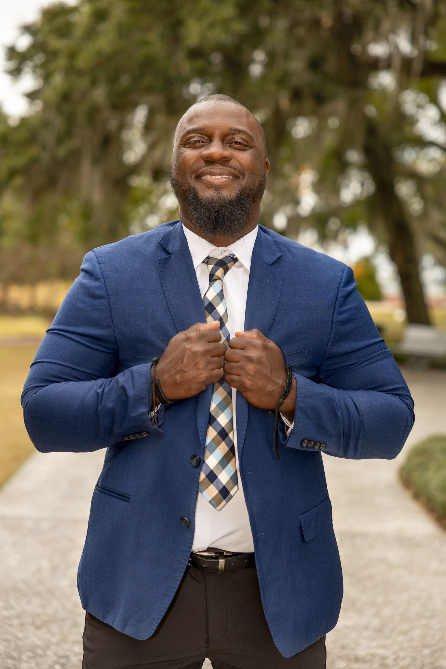 Professional portrait series showing person in navy suit and plaid tie making confident poses.