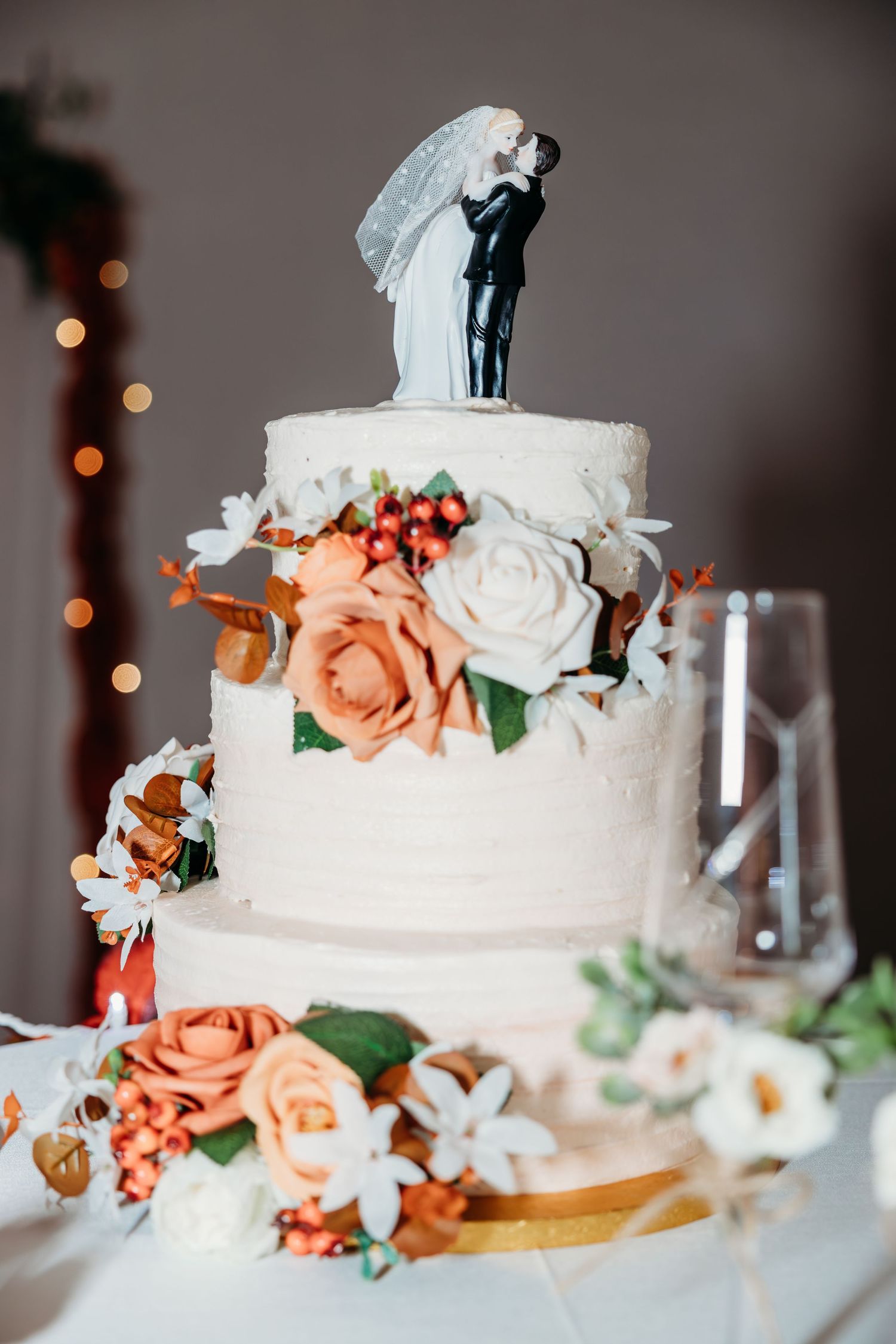 Elegant white wedding cake decorated with peach roses and floral accents.