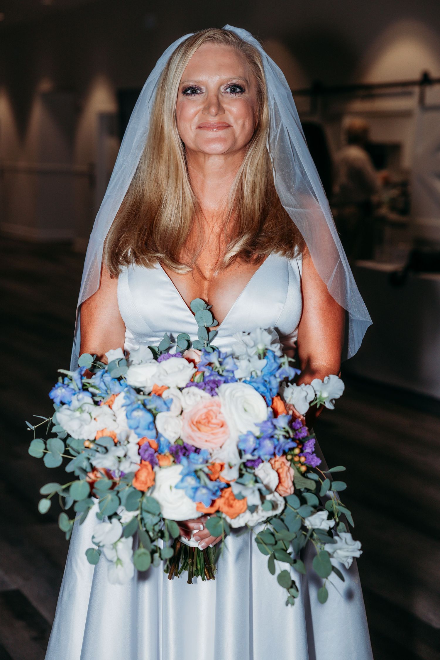 Beautiful bridal bouquet featuring blue, peach and white flowers with eucalyptus greenery.