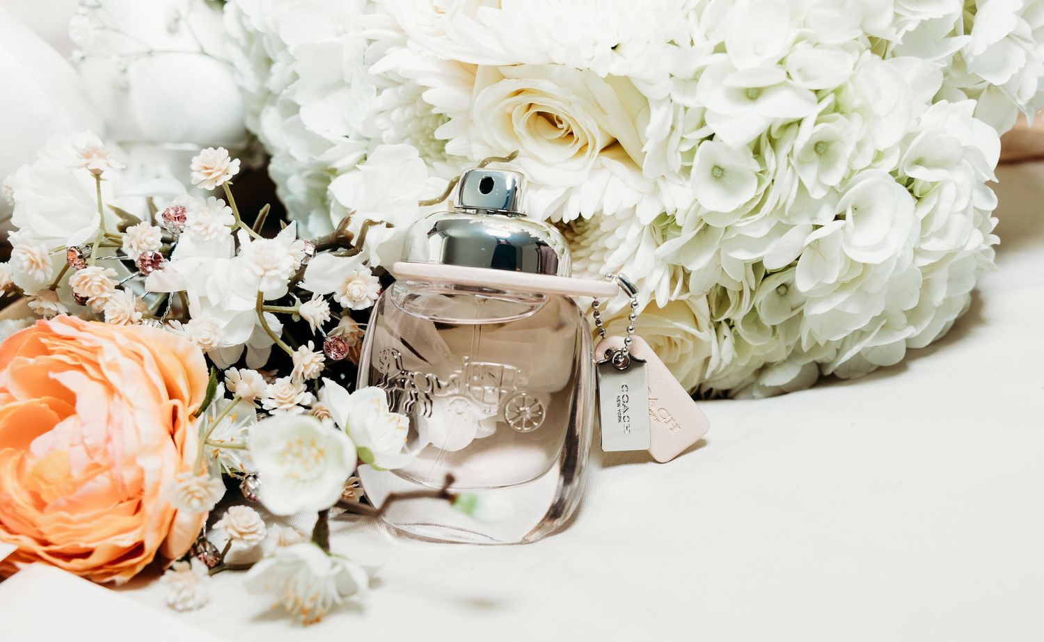 Delicate white and peach floral arrangements with roses and hydrangeas create an elegant wedding backdrop.