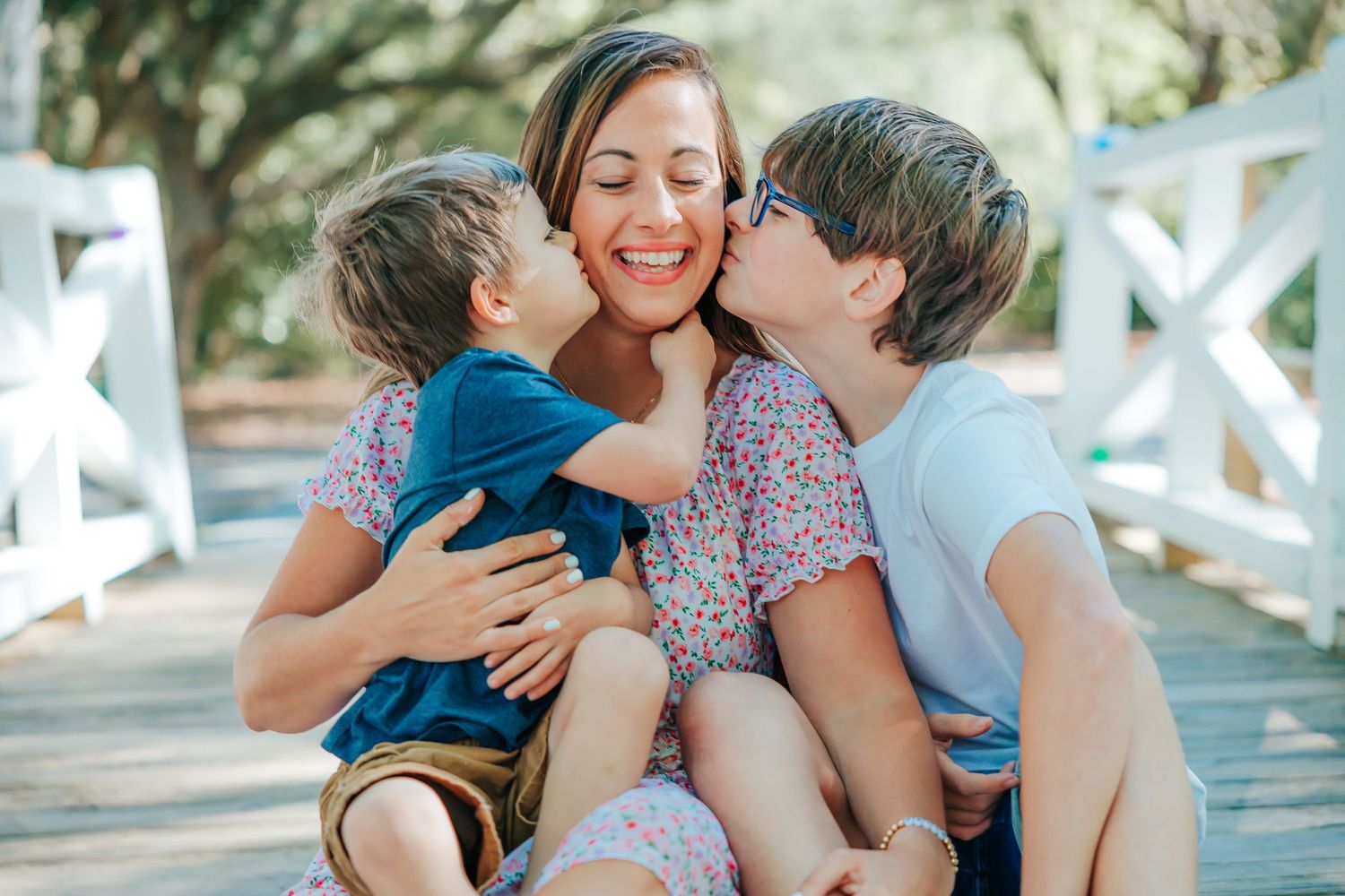 Tender family moment captured on a white wooden bridge during an outdoor photo session.