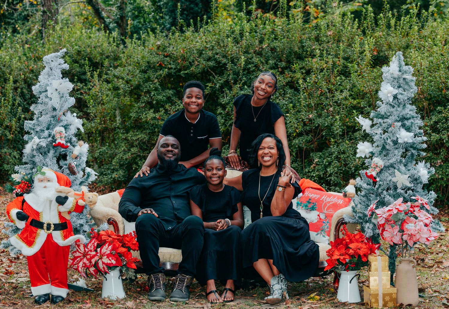 Family photo session setup with floral decorations and white Christmas trees in an outdoor garden setting.