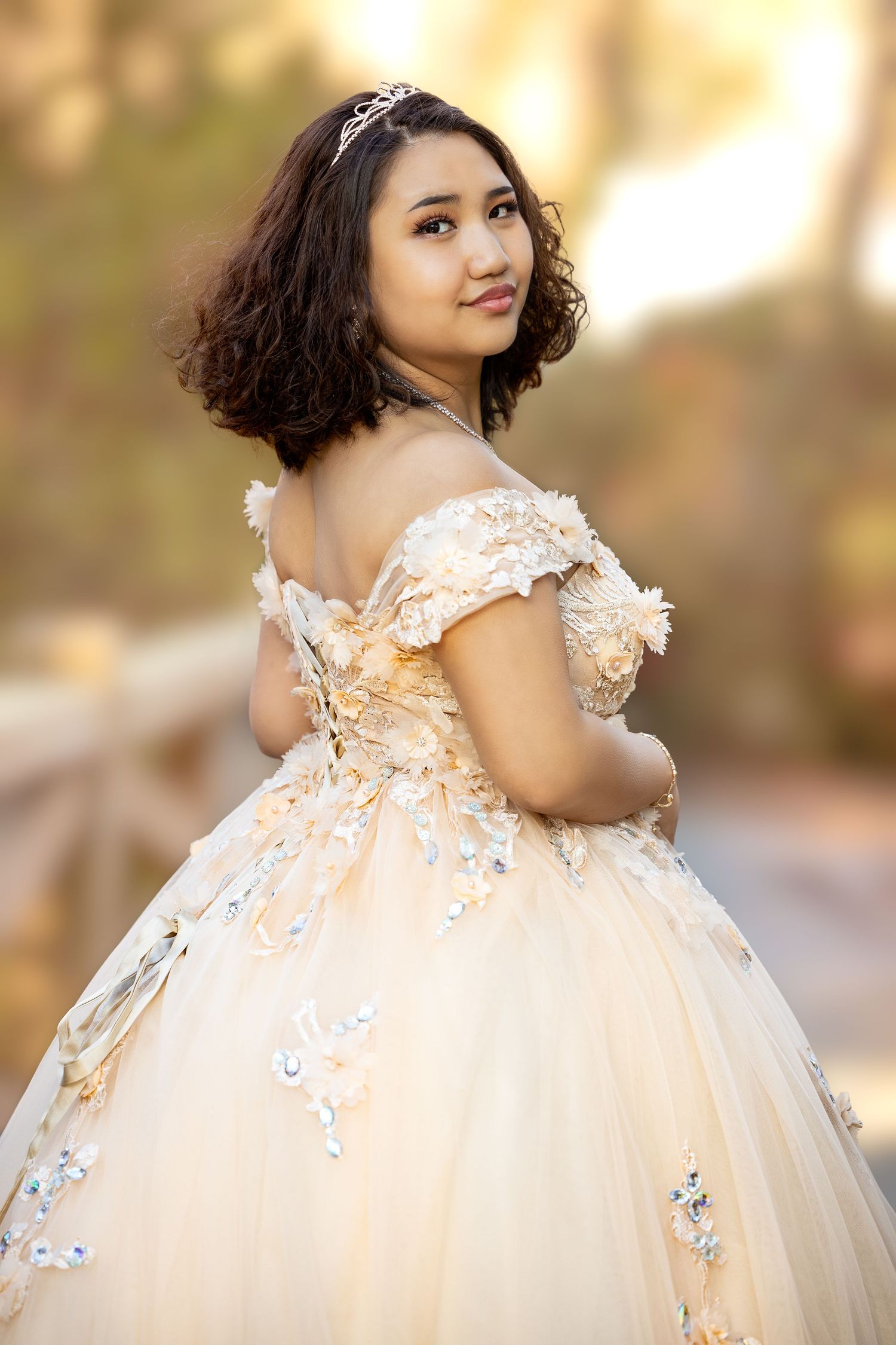 Close-up details of champagne-colored quinceañera dress with floral appliques and crystals.