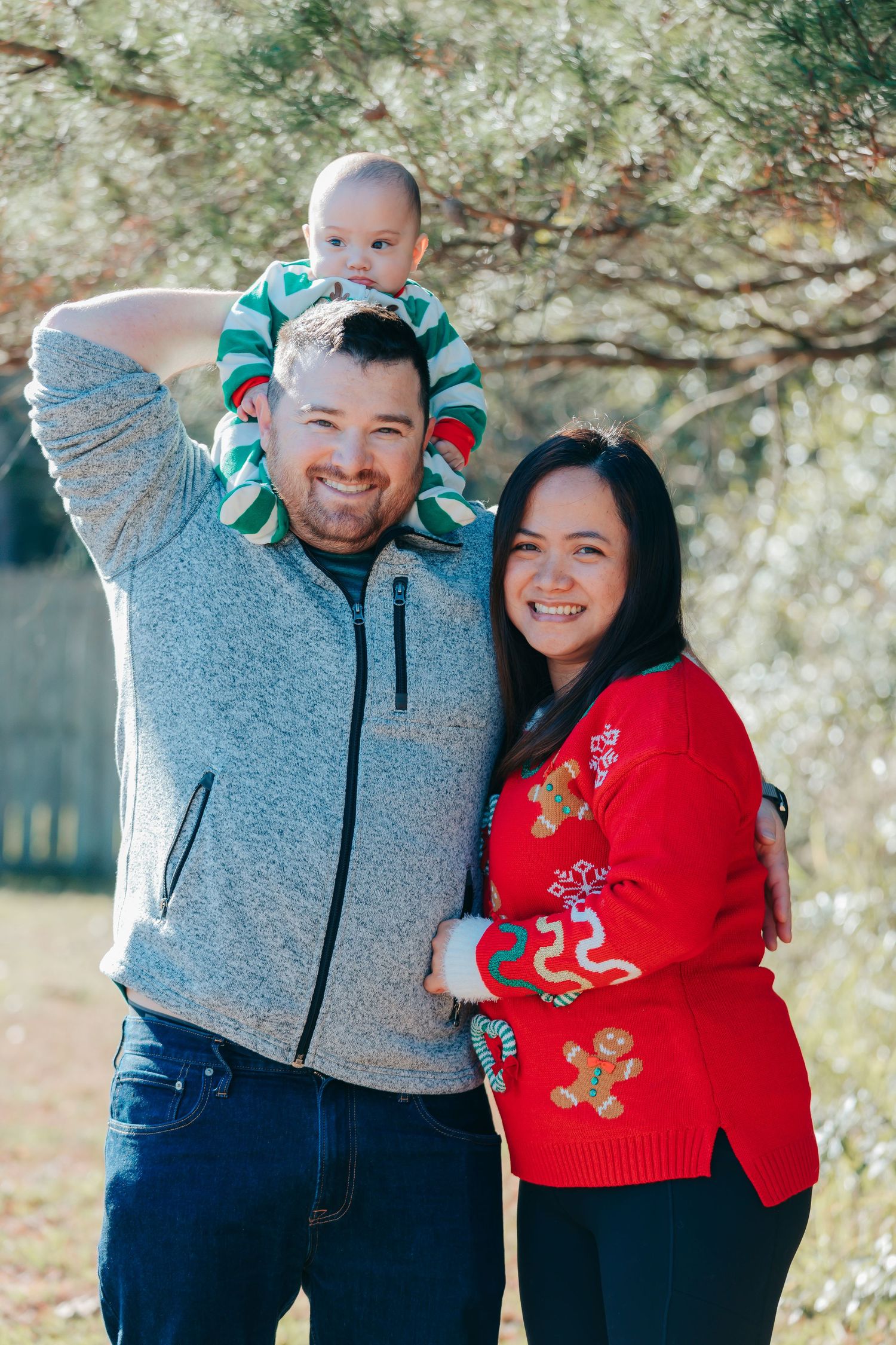 Couple wearing festive holiday sweaters pose playfully together outdoors.
