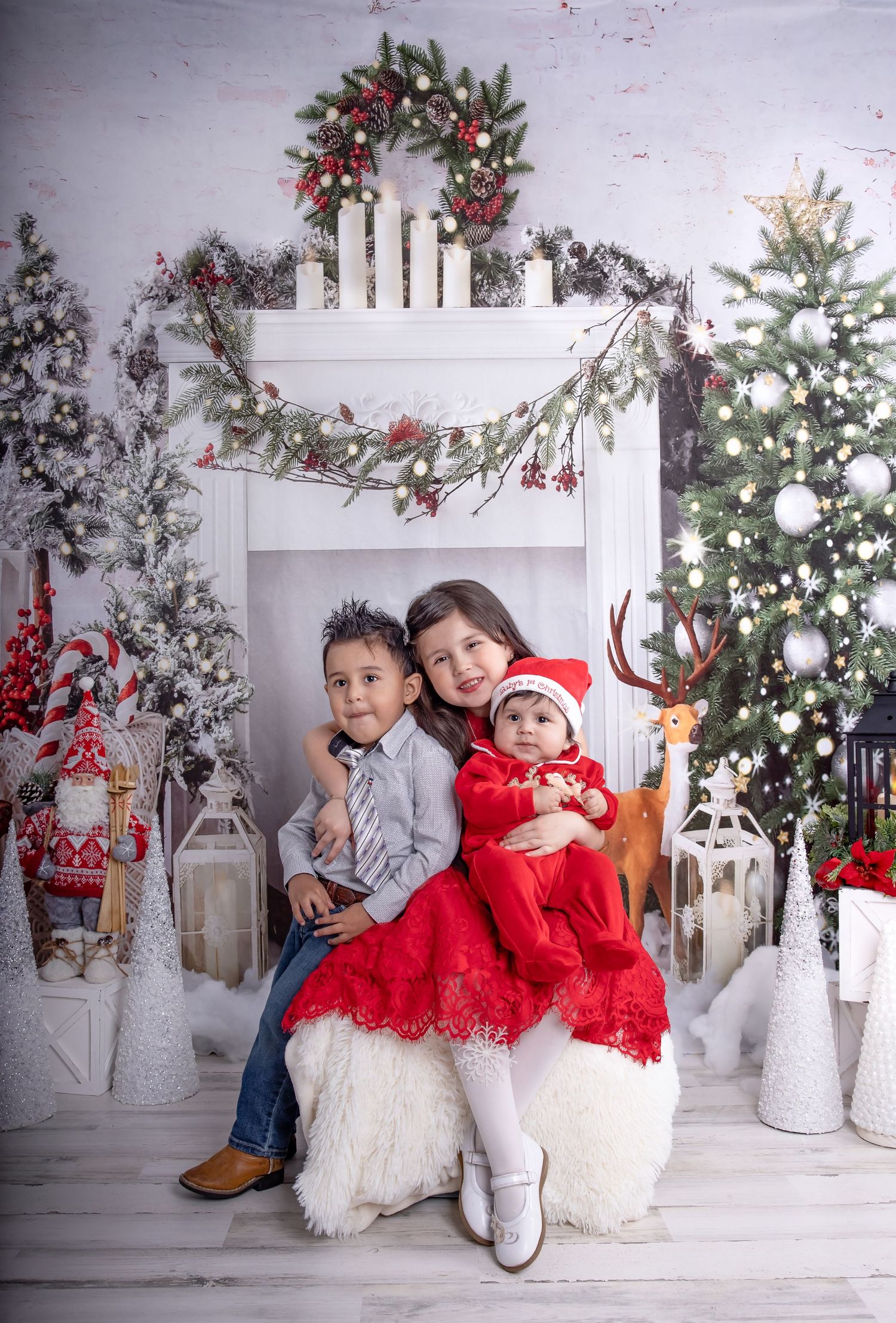 Holiday photo setup with white and red decorations, Christmas trees, and festive props.