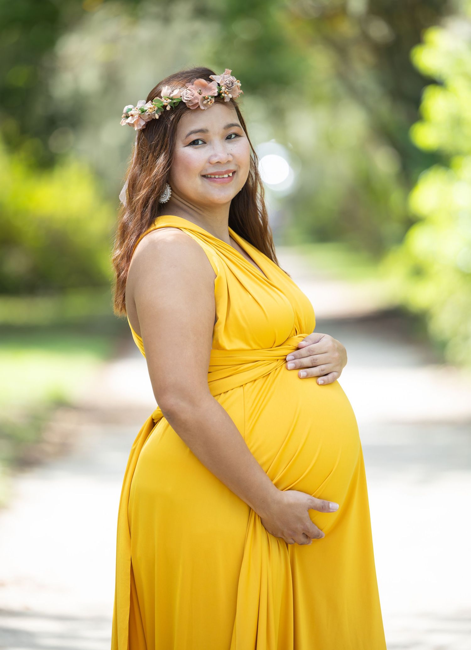 A series of maternity photos showing a woman in a bright yellow maxi dress posing in a garden setting.