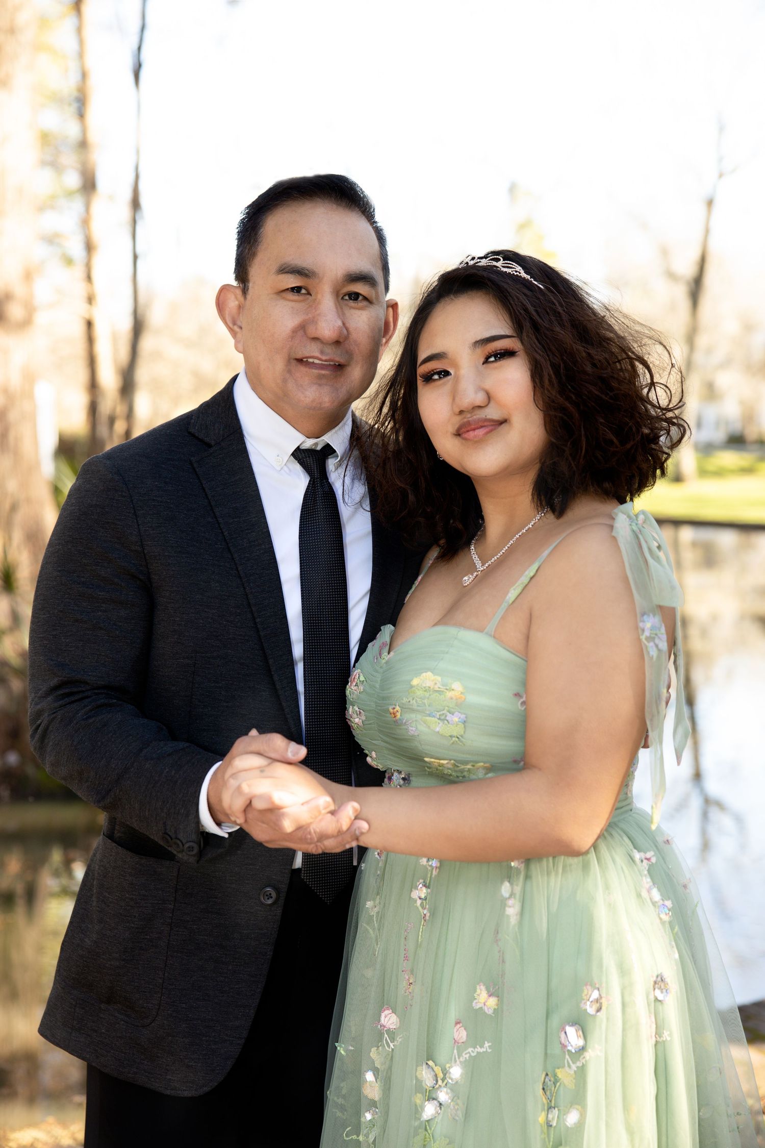 Couple in formal attire poses for engagement photos in mint green dress and black suit.