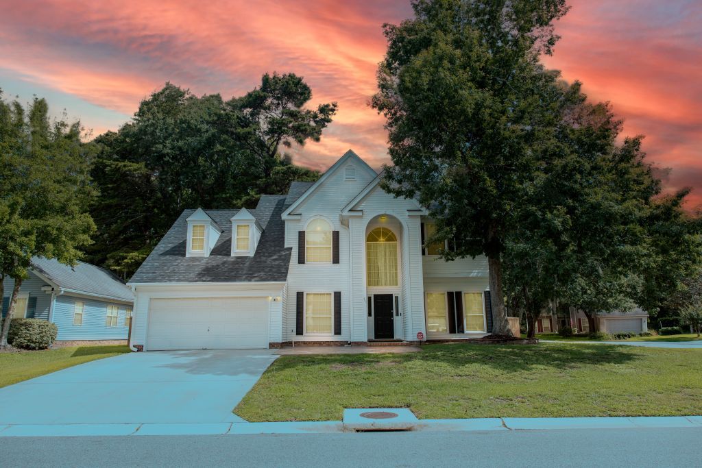Large white colonial style home with two-car garage during vibrant sunset.