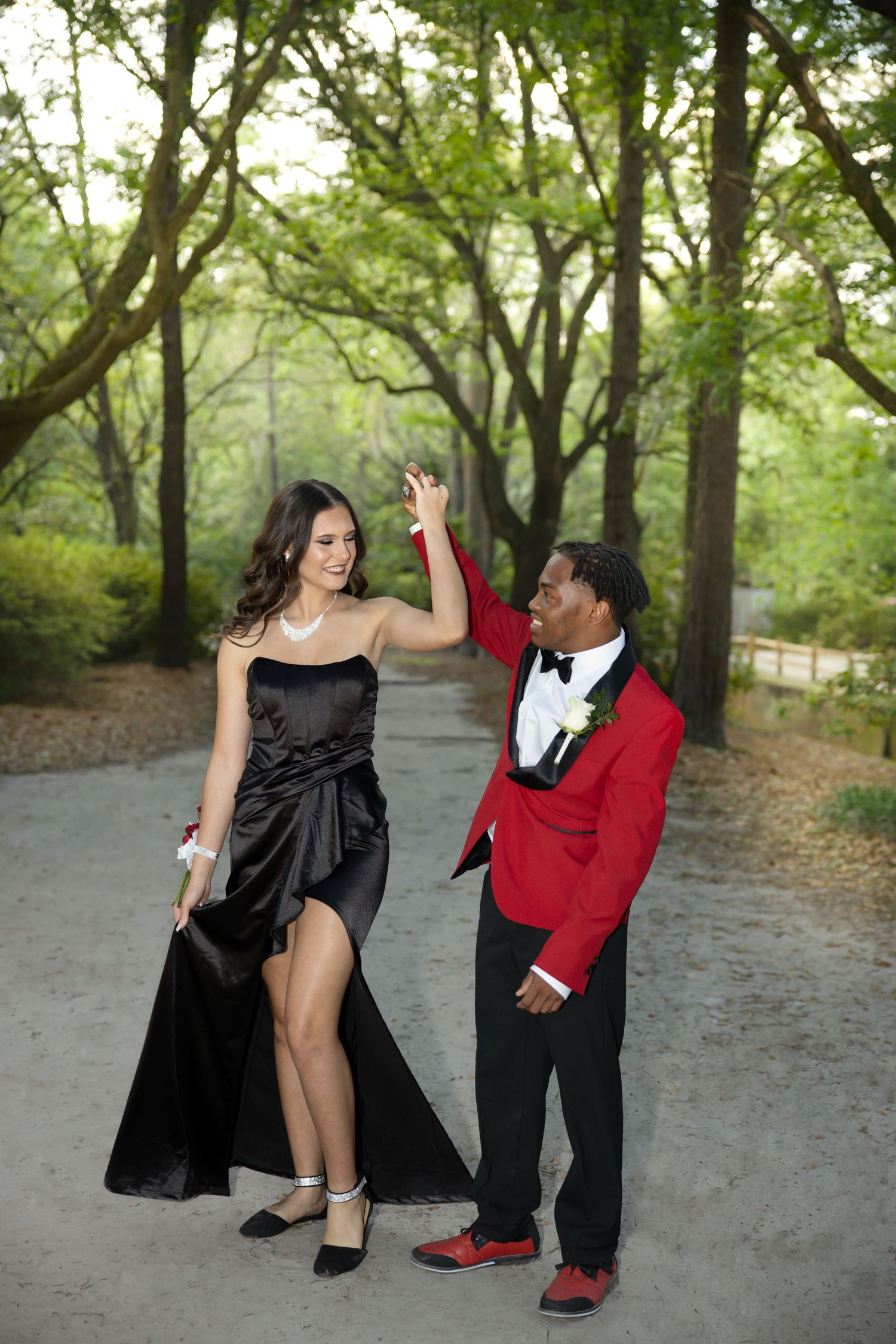 Couple in formal attire strikes dynamic poses on park path.