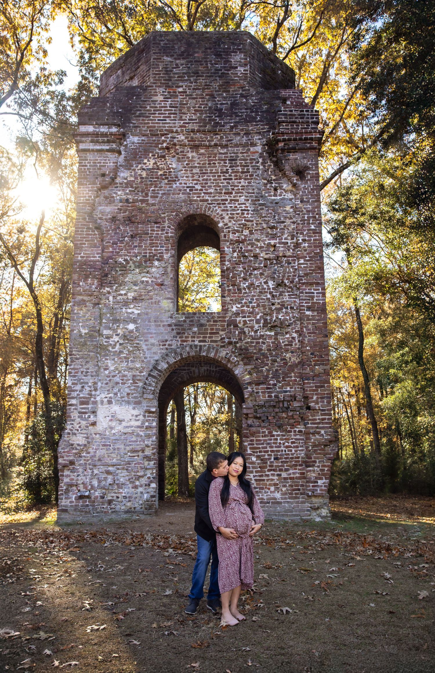 Couple shares tender moment by historic brick ruins during autumn photoshoot.