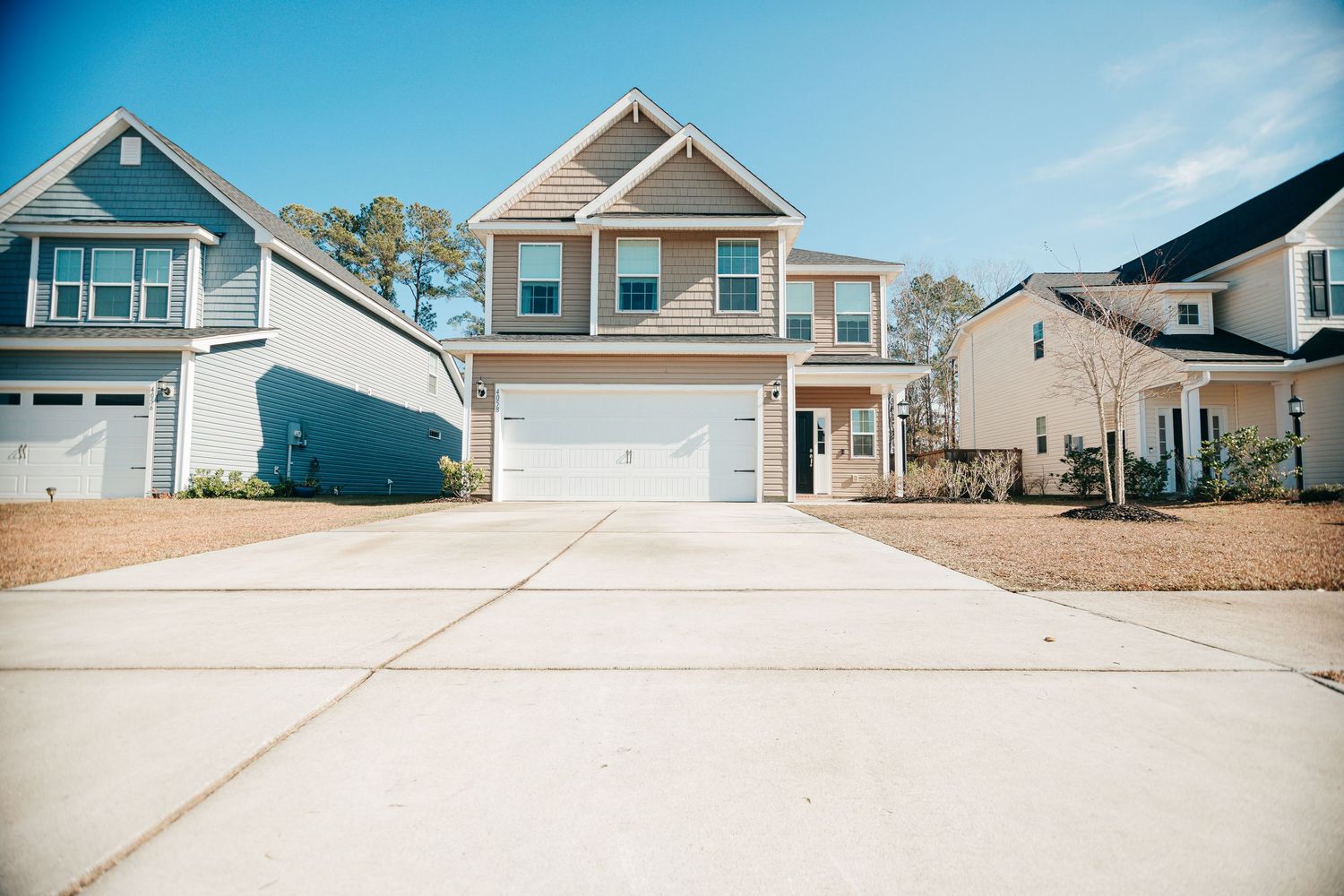 Row of modern townhouses with blue and gray siding under clear blue sky.