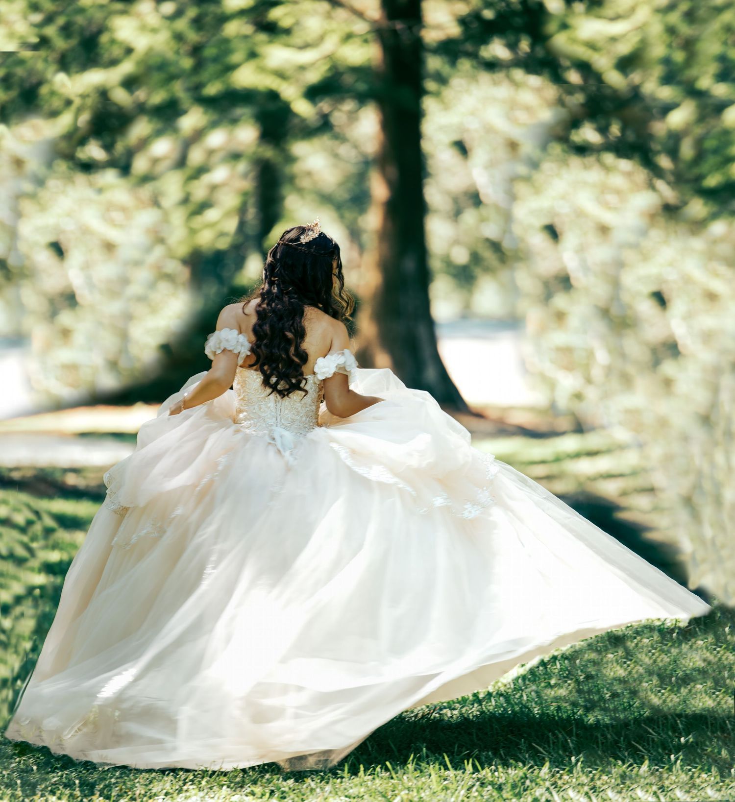 A flowing white dress twirls gracefully in a sunny garden setting with trees in the background.