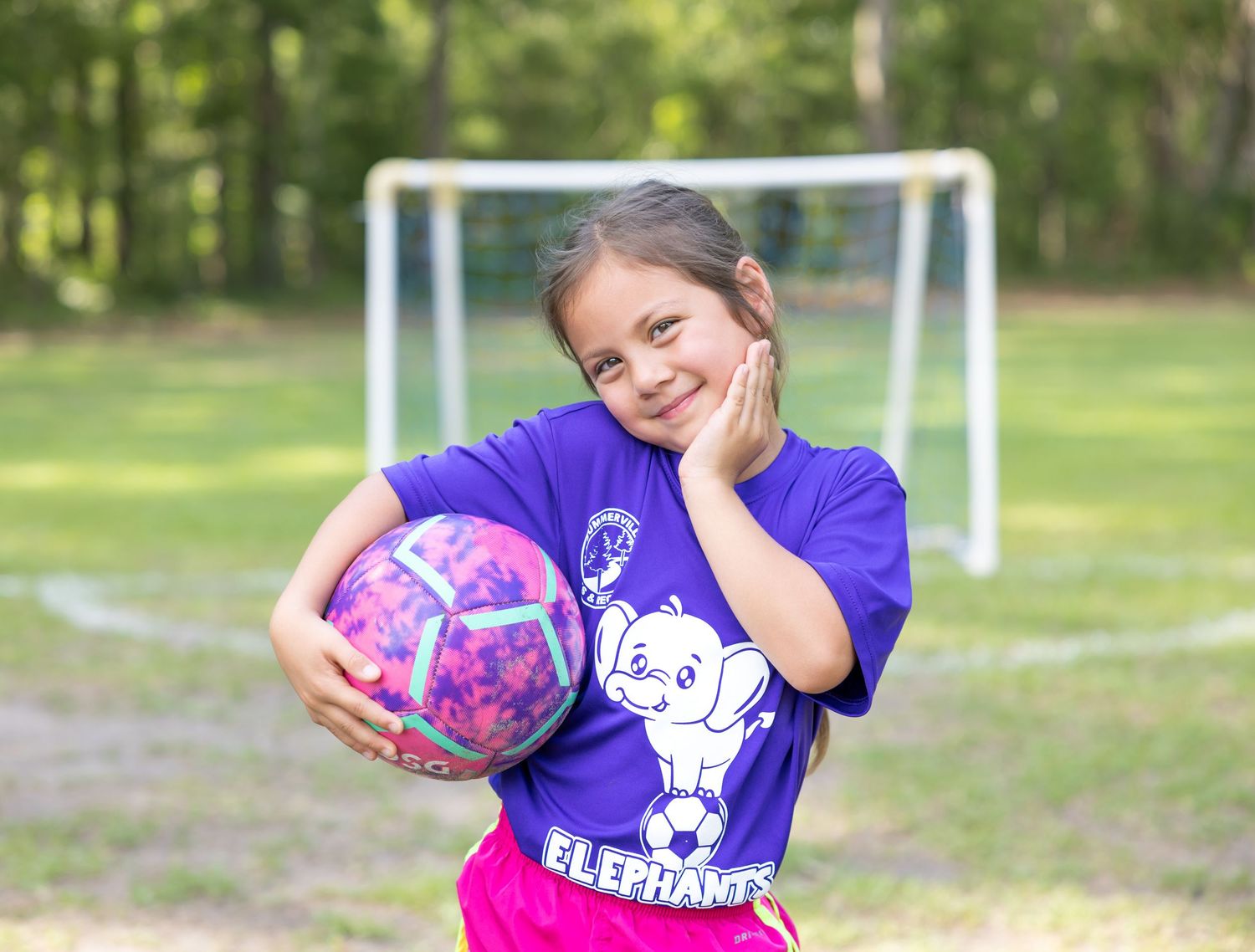 Young soccer players in purple jerseys practicing their skills on a sunny field.