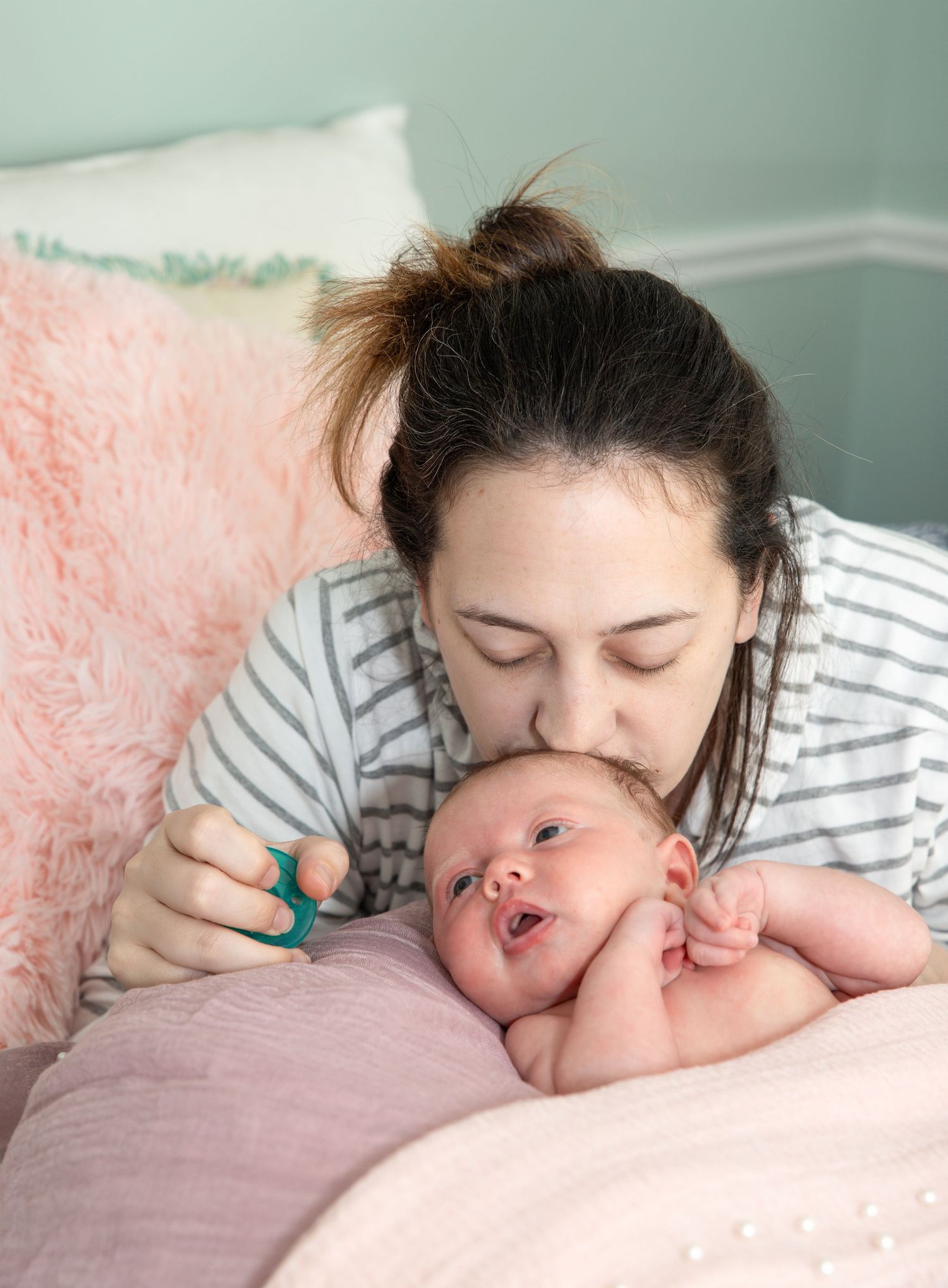 Intimate bonding moment between parent and newborn baby on pink bedding.