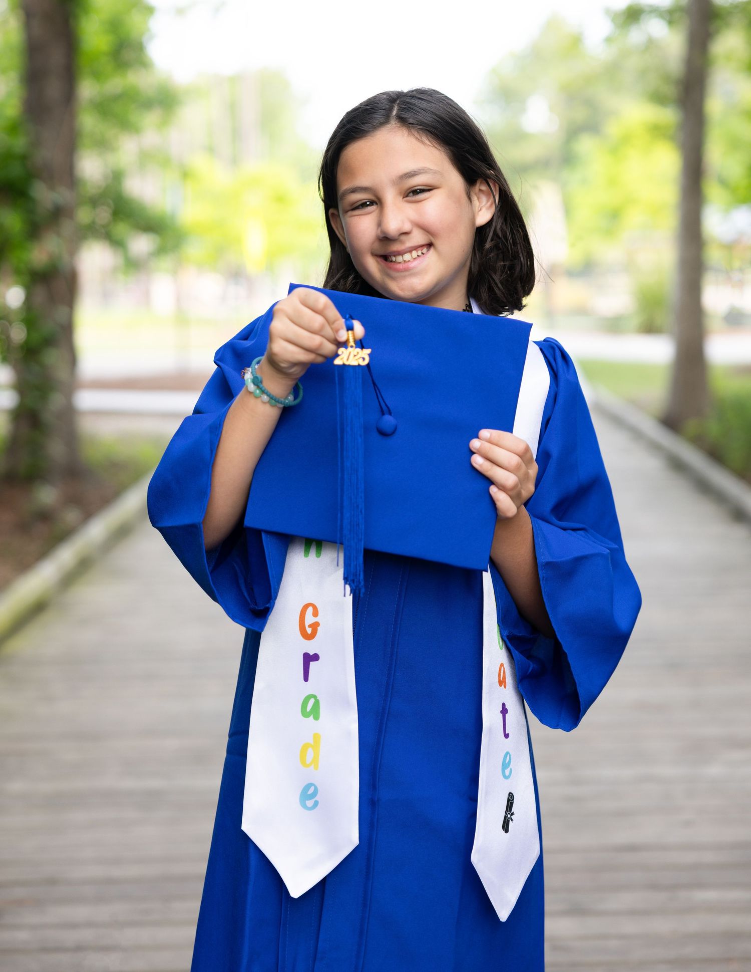 Graduate in blue cap and gown displays decorated graduation stole.