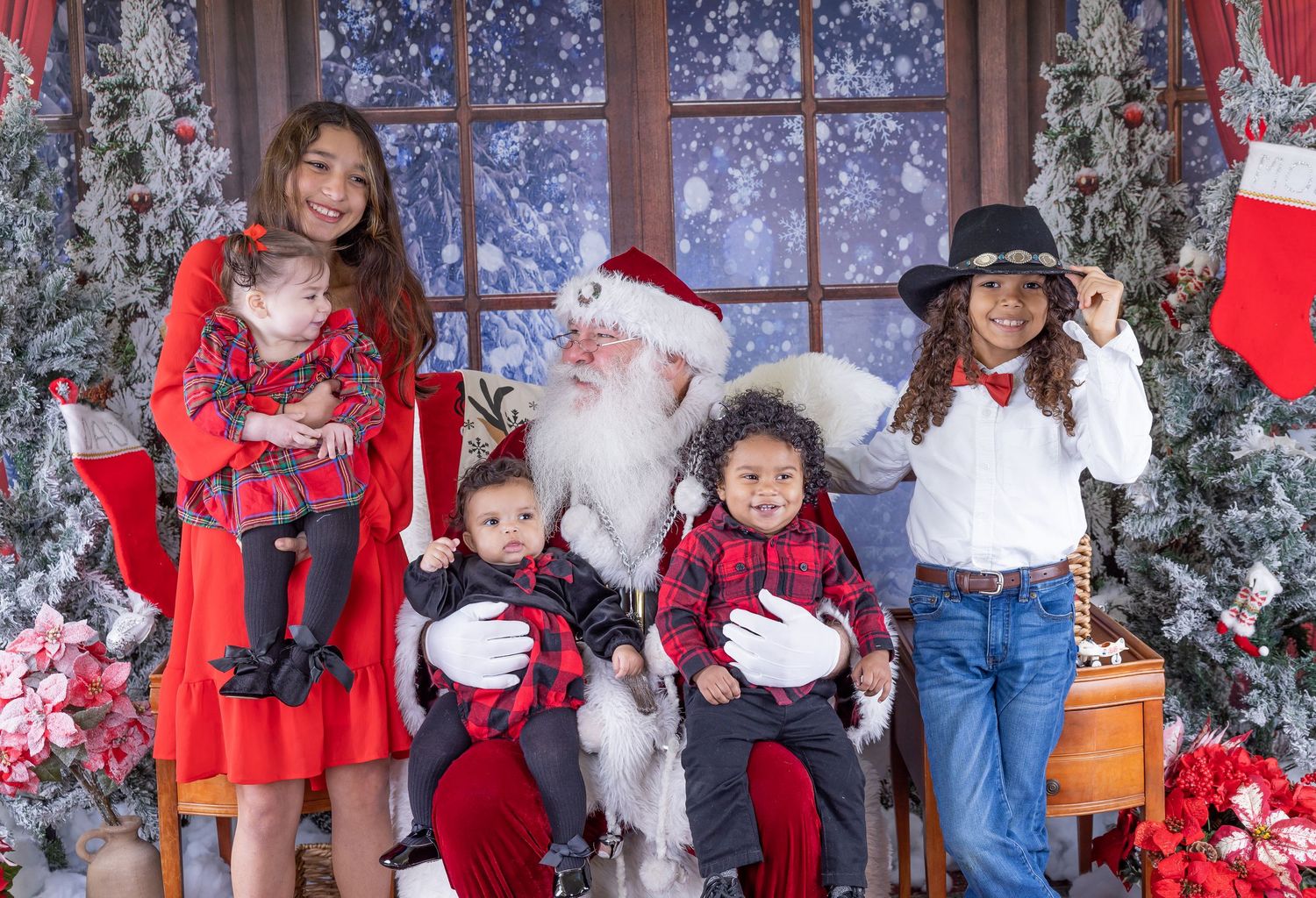 Christmas photo studio setup with decorated trees, red curtains, and holiday props.
