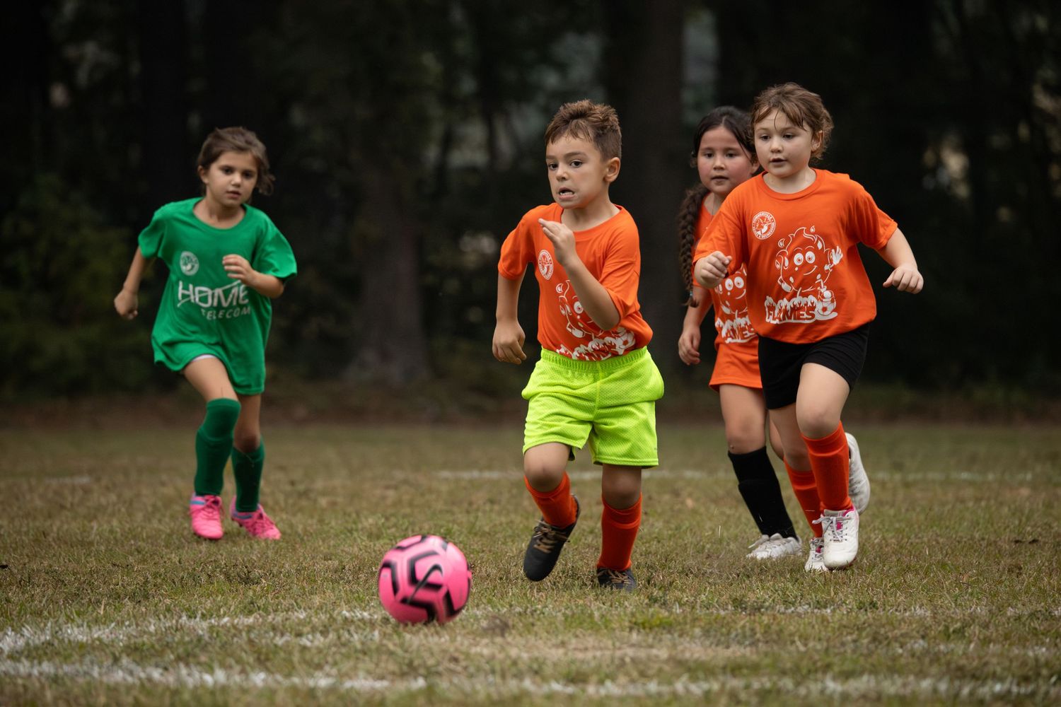 Youth soccer players in colorful uniforms running during a practice session.
