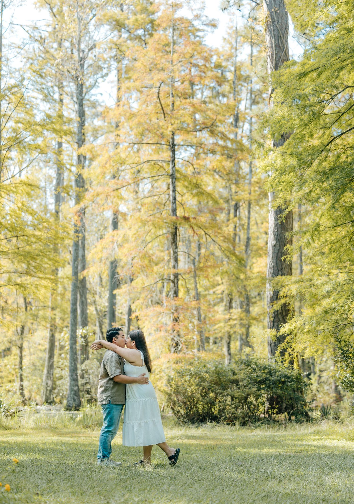 Couple shares romantic moments in a sunlit autumn forest setting.