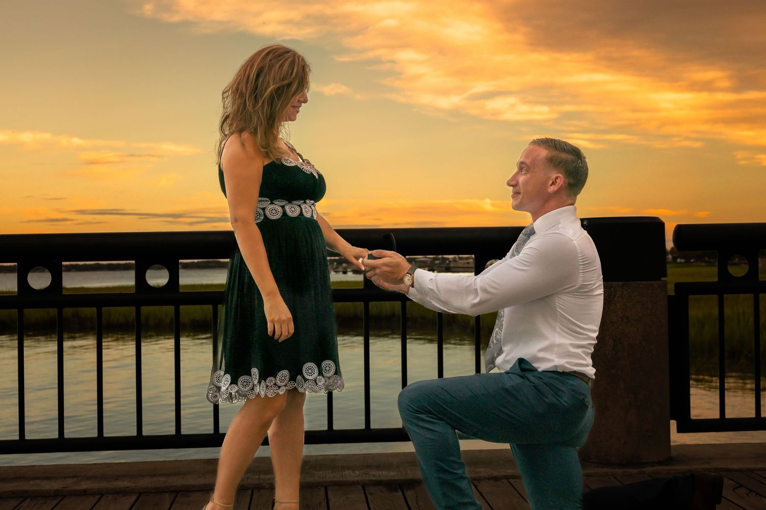 Sunset proposal moment captured at Charleston waterfront with dramatic lighting.