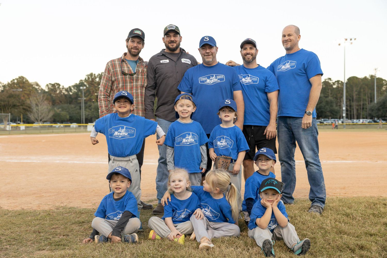 Youth baseball team in blue uniforms posing together on a sports field.
