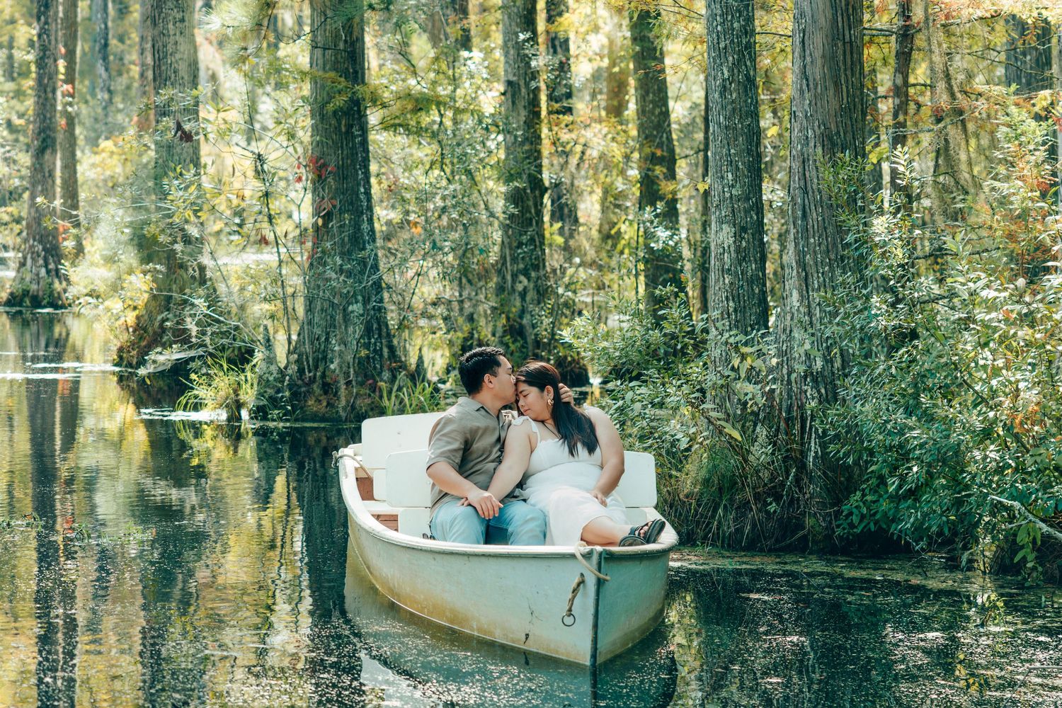 Couple enjoys a romantic boat ride through a cypress swamp on a sunny day.