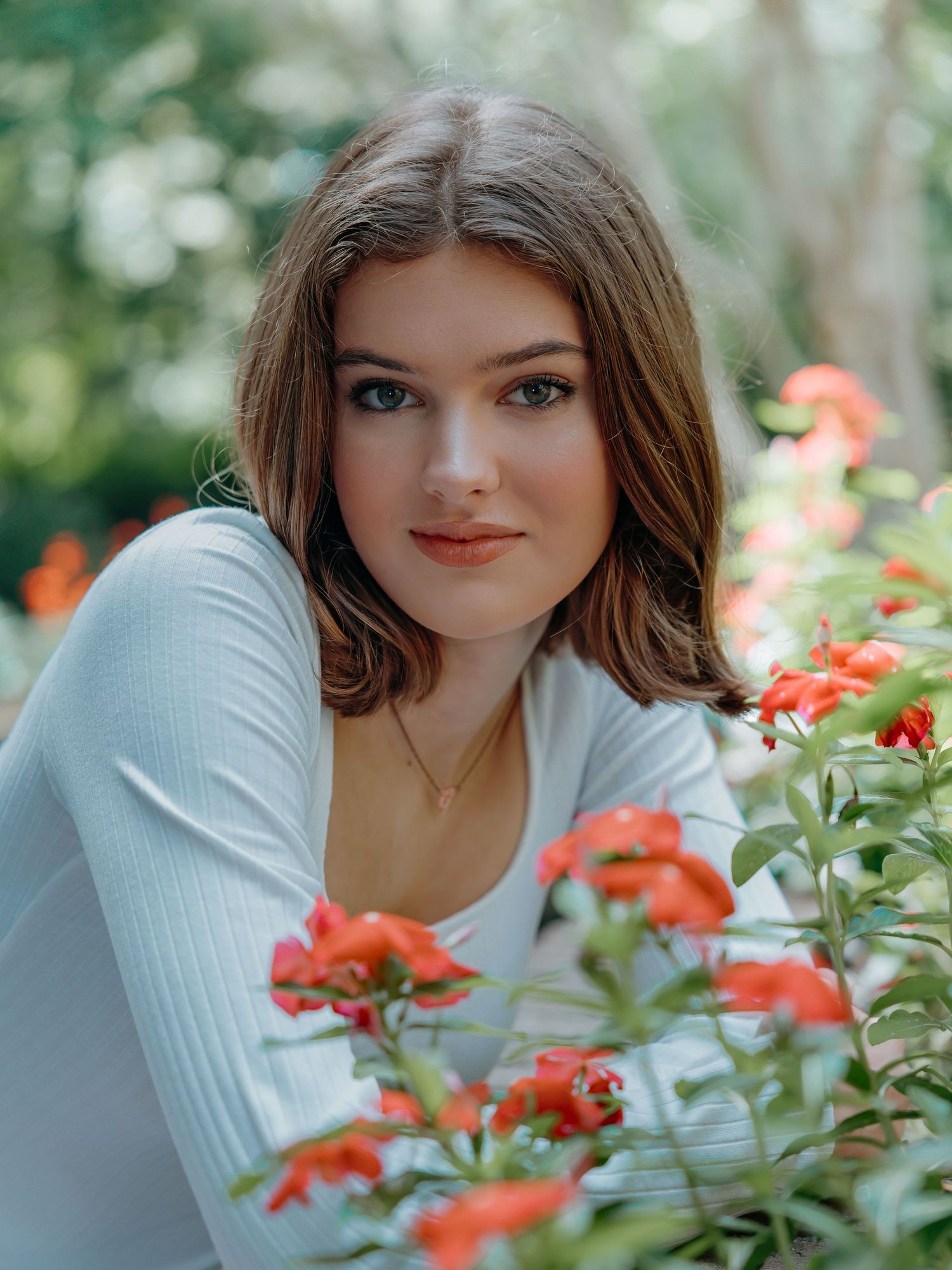 A white sweater-clad figure poses among vibrant orange flowers in a garden setting.